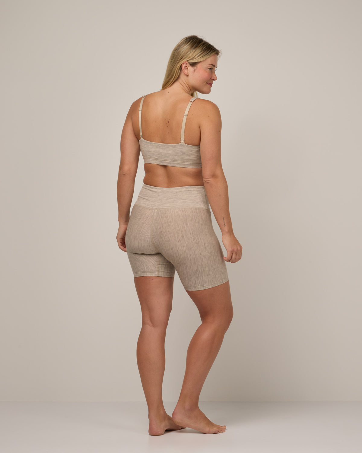 Model wearing Roam Bike Short in Oatmeal Heather, a soft heathered cream color. Roam Bike Short is a merino wool short with pockets available in sizes XS-3X.