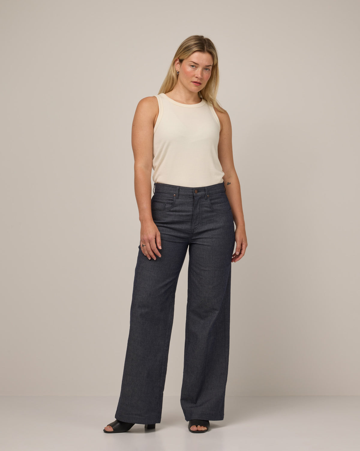 Model wearing Beck Wide Leg Denim Jean in Indigo Blue. Beck Wide Leg Denim Jean is a merino wool pant with pockets available in sizes 26-34.