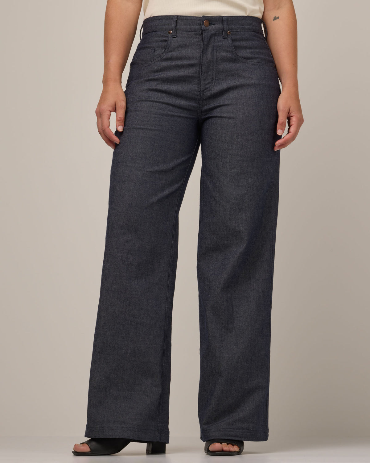 Model wearing Beck Wide Leg Denim Jean in Indigo Blue. Beck Wide Leg Denim Jean is a merino wool pant with pockets available in sizes 26-37.