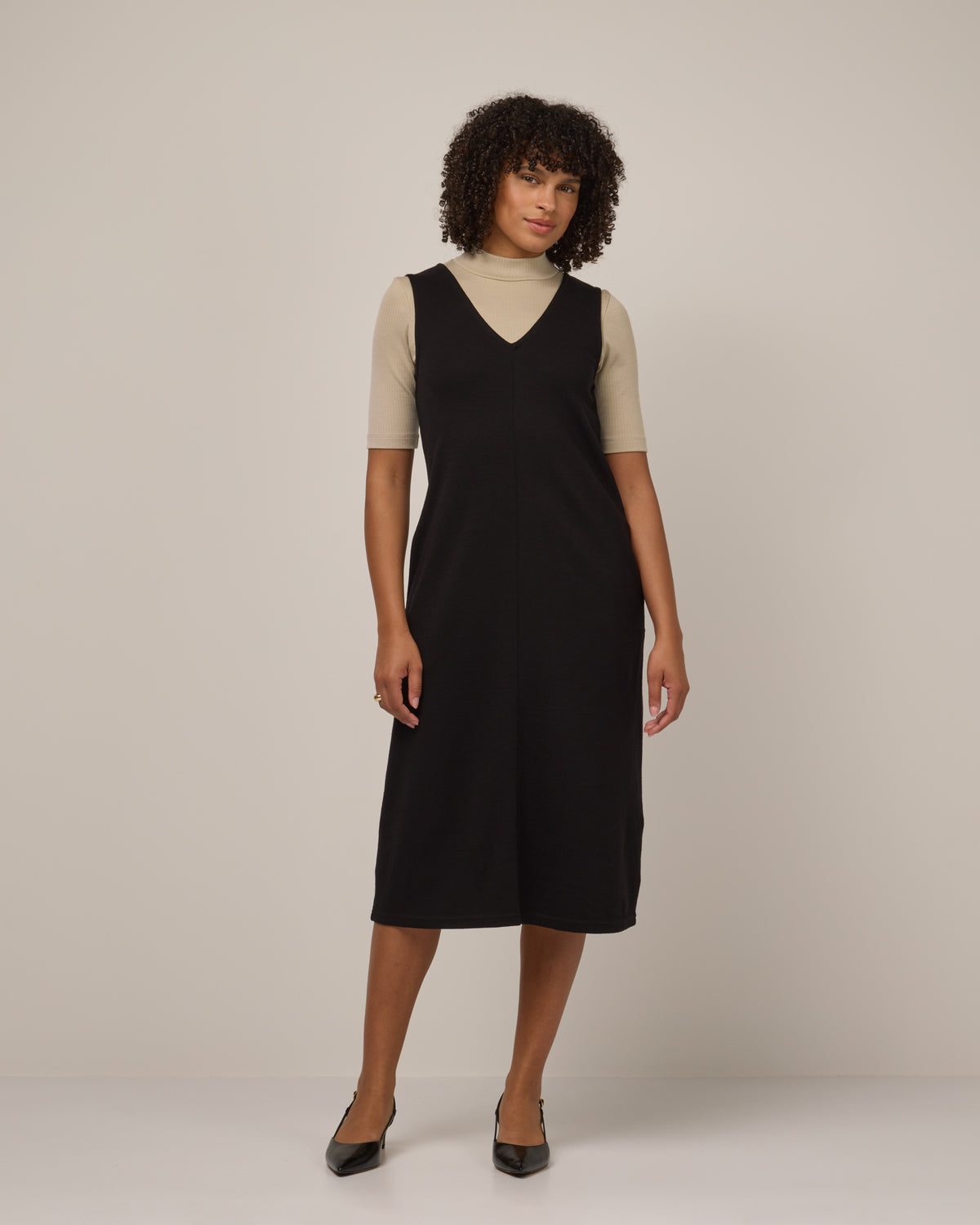 Model wearing Jessa Reversible Dress in Black. Jessa Reversible Dress is a merino wool sleeveless, reversible, midi shift dress with pockets available in sizes XS-3X.