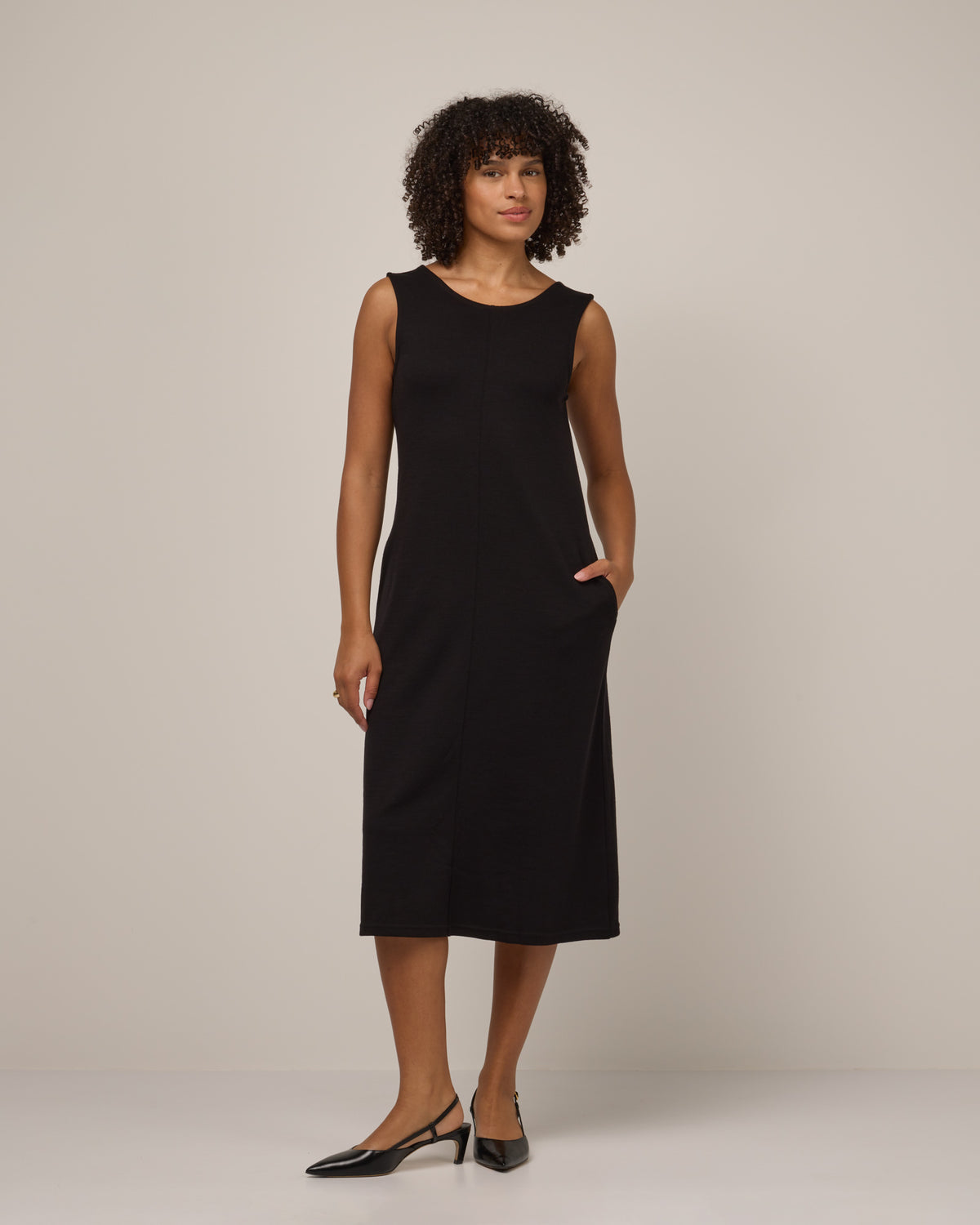 Model wearing Jessa Reversible Dress in Black. Jessa Reversible Dress is a merino wool sleeveless, reversible, midi shift dress with pockets available in sizes XS-3X.