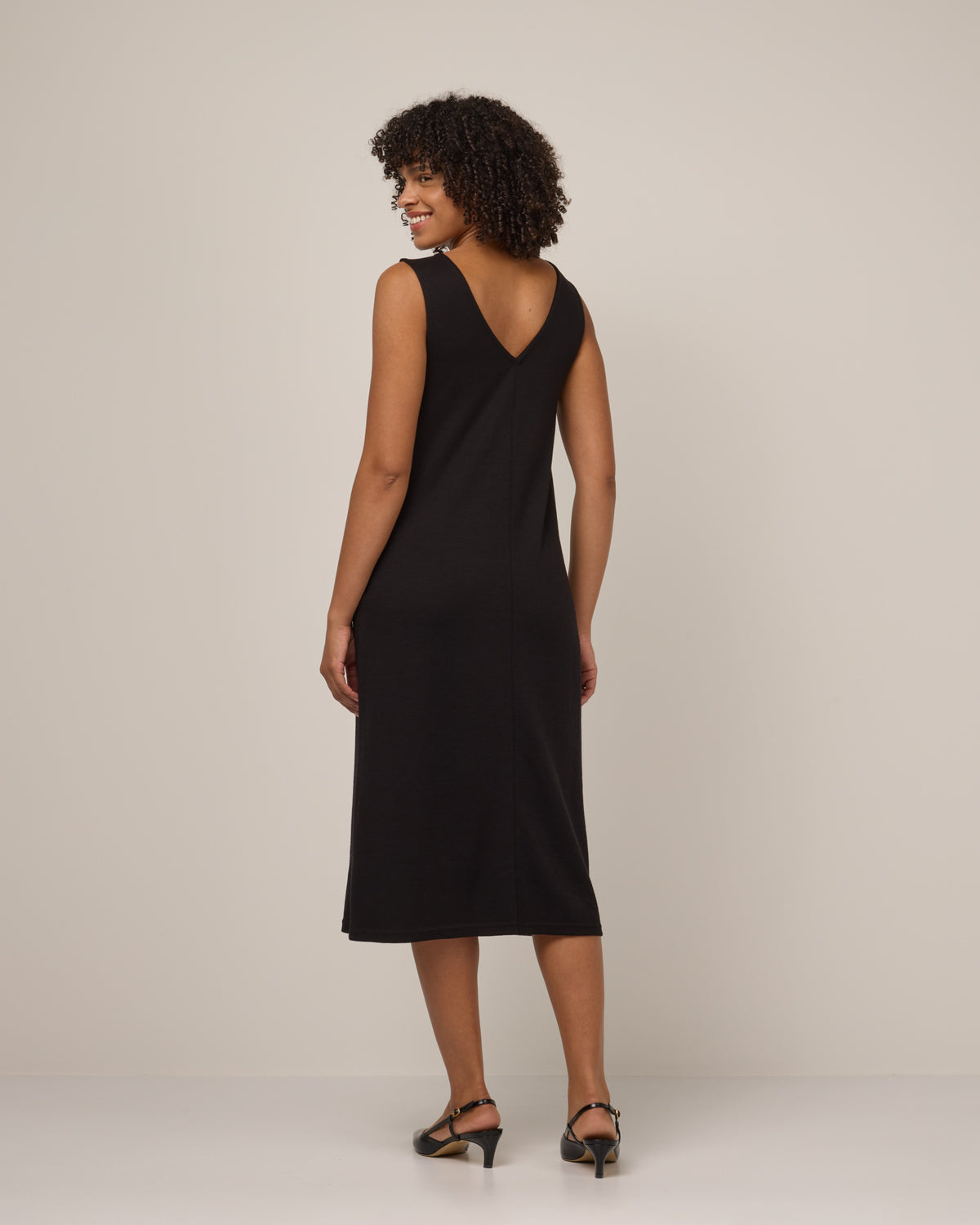 Model wearing Jessa Reversible Dress in Black. Jessa Reversible Dress is a merino wool sleeveless, reversible, midi shift dress with pockets available in sizes XS-3X.