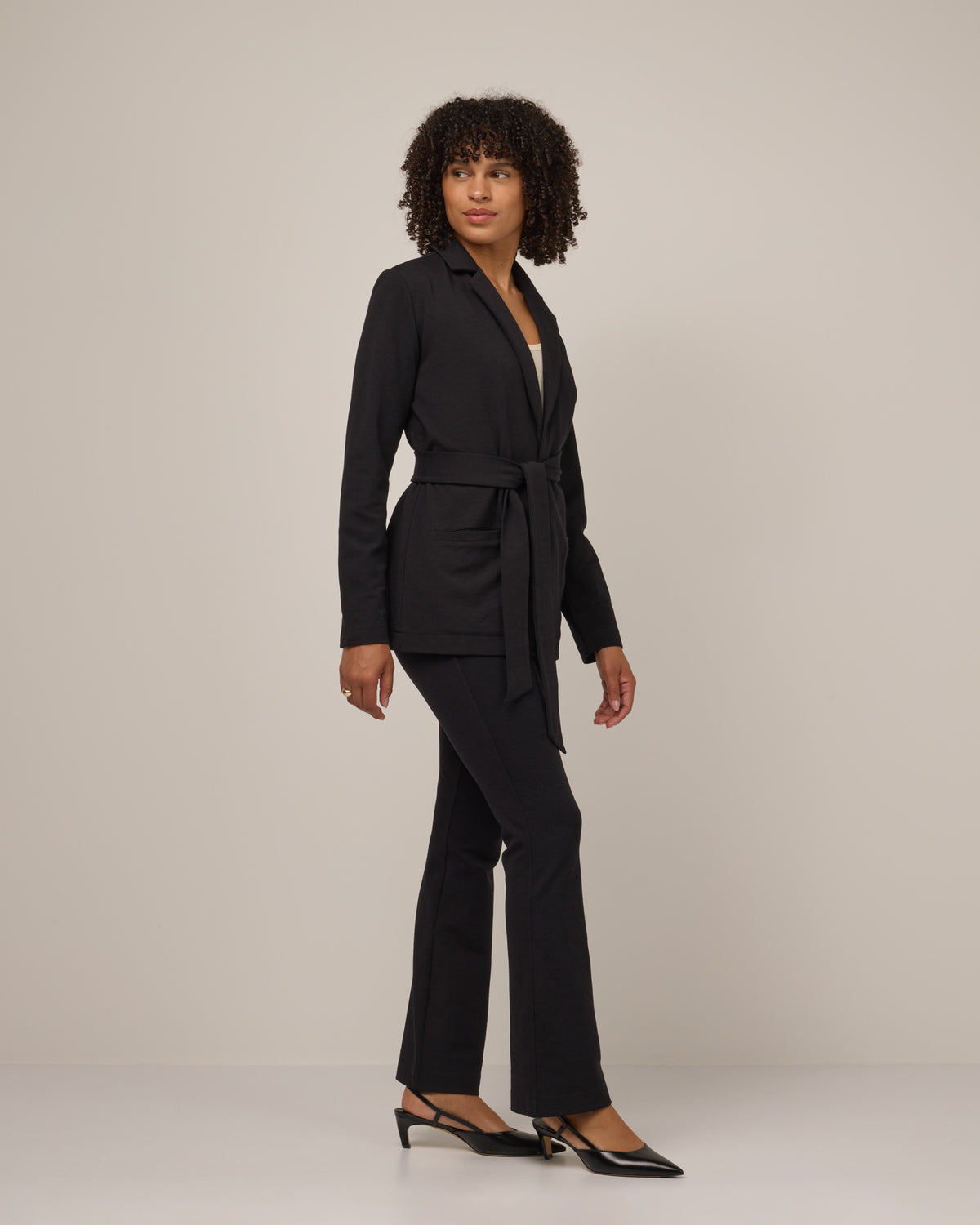 Model wearing Kristen Blazer in Black. Kristen Blazer is a merino wool long sleeve, collared, regular fit jacket with pockets available in sizes XS-XXL.