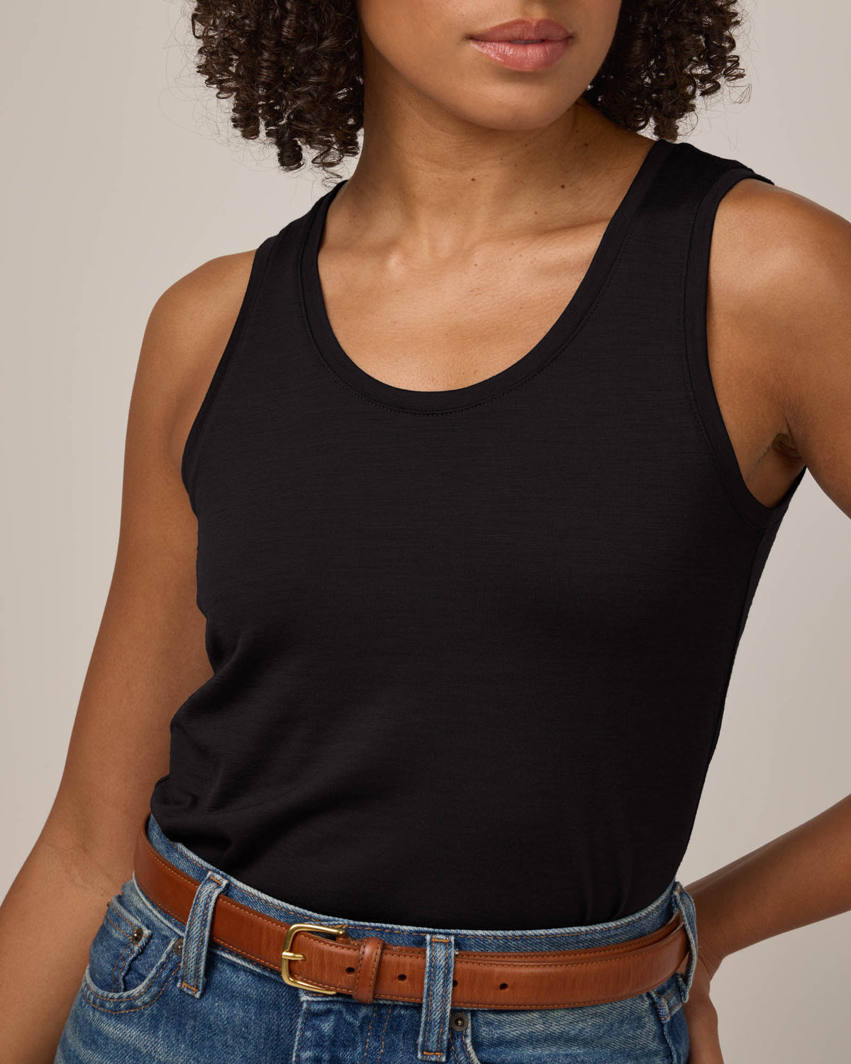 Model wearing Livia Fitted Tank in Black. Livia Fitted Tank is a merino wool sleeveless, scoop neck, slim fit top available in sizes XS-3X.