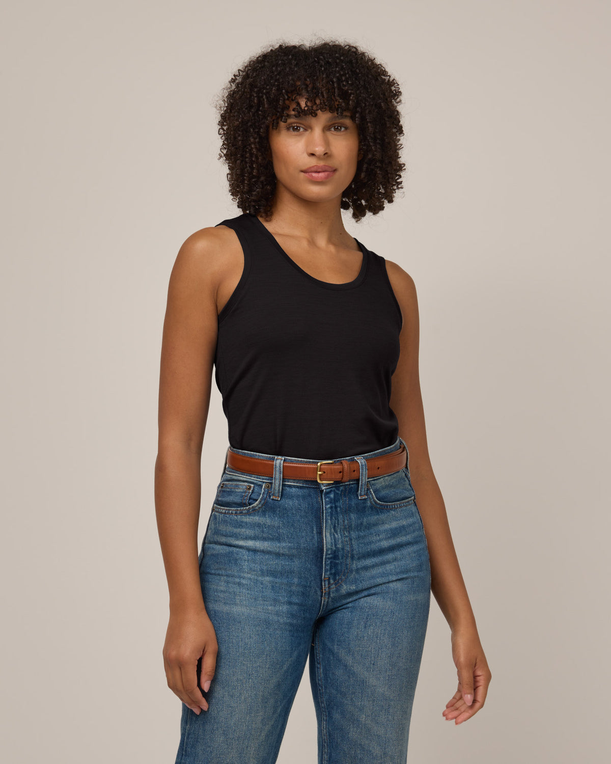 Model wearing Livia Fitted Tank in Black. Livia Fitted Tank is a merino wool sleeveless, scoop neck, slim fit top available in sizes XS-3X.