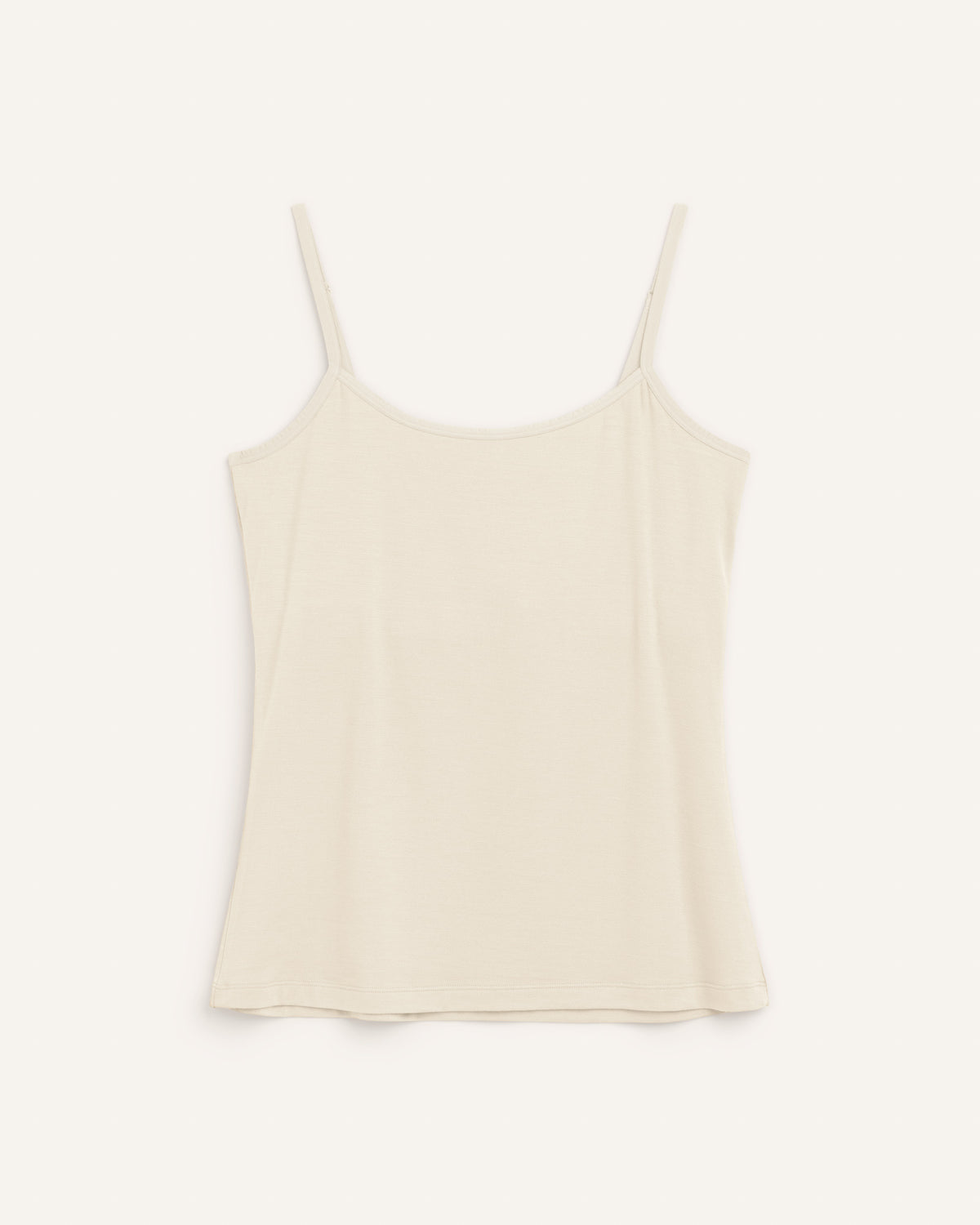 Laydown of Roam Shelf Bra Cami in Natural White, an off-white cream color. Roam Shelf Bra Cami is a merino wool sleeveless, scoop neck, slim fit top available in sizes XS-XXL.