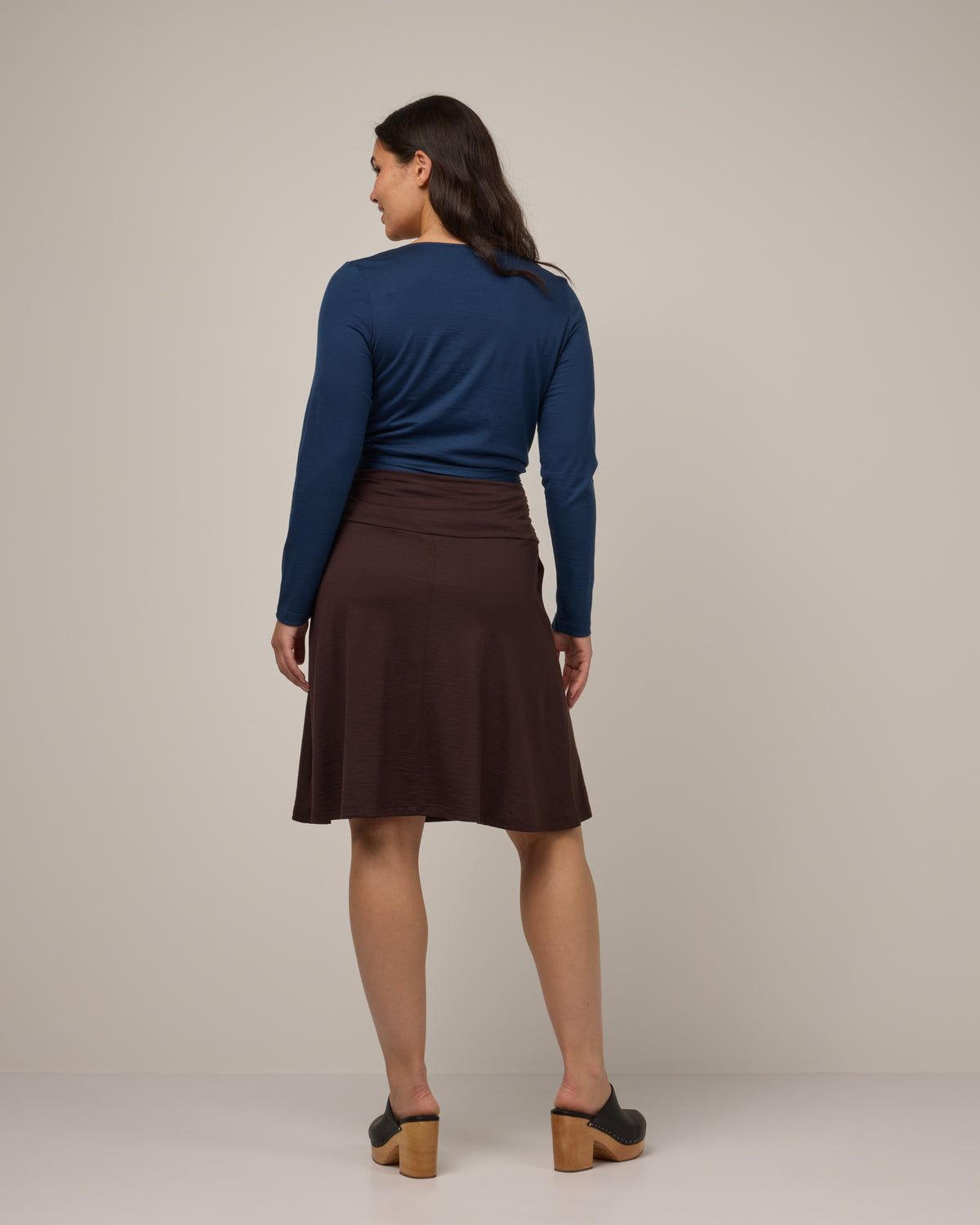 Model wearing Helena Skirt in Espresso, a dark brown color. Helena Skirt is a merino wool knee length skirt with pockets available in sizes XS-3X.