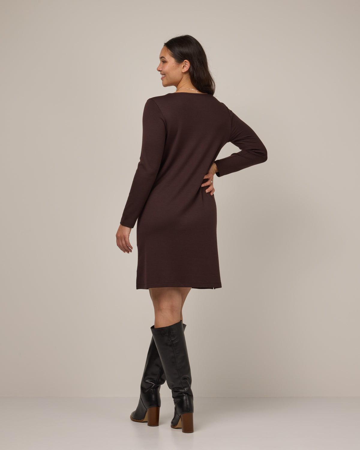 Model wearing Margo Shift Dress in Espresso, a dark brown color. Margo Shift Dress is a merino wool long sleeve, boatneck, knee length shift dress with pockets available in sizes XS-3X Regular, S-3X Long.
