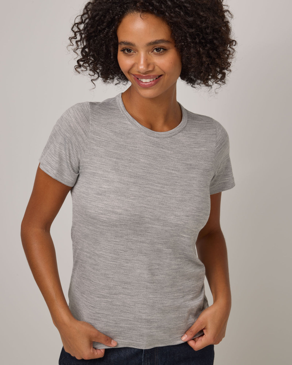 Model wearing Cara Signature Fitted Tee in Gray Heather. Cara Signature Fitted Tee is a merino wool short sleeve, crew neck, slim fit tee available in sizes XS-3X.
