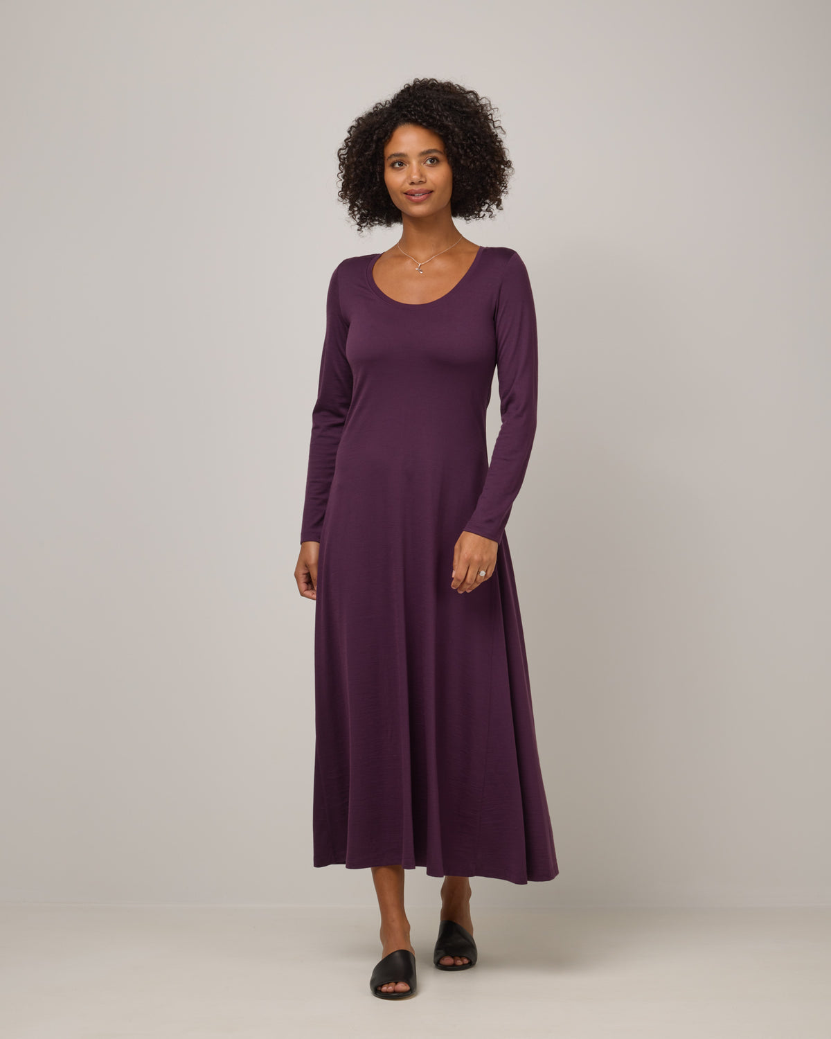 Model wearing Valerie Maxi Dress in Marionberry, a dark berry purple color. Valerie Maxi Dress is a merino wool long sleeve, scoop neck, maxi swing dress available in sizes XS-XXL.