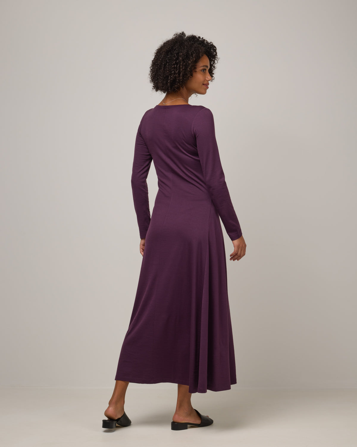 Model wearing Valerie Maxi Dress in Marionberry, a dark berry purple color. Valerie Maxi Dress is a merino wool long sleeve, scoop neck, maxi swing dress available in sizes XS-XXL.
