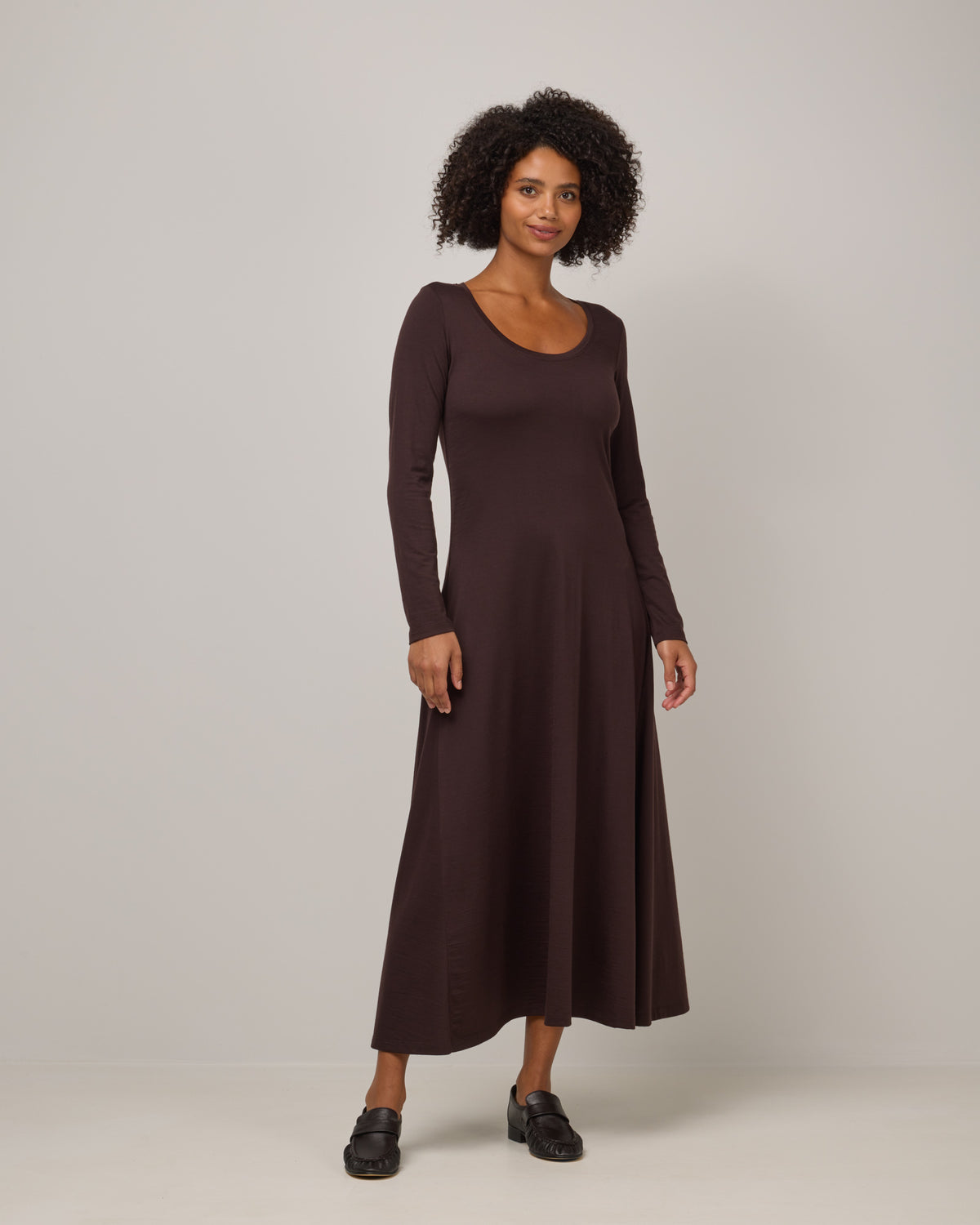 Model wearing Valerie Maxi Dress in Espresso, a dark brown color. Valerie Maxi Dress is a merino wool long sleeve, scoop neck, maxi swing dress available in sizes XS-XXL.
