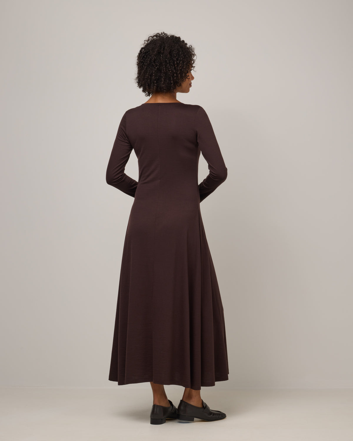 Model wearing Valerie Maxi Dress in Espresso, a dark brown color. Valerie Maxi Dress is a merino wool long sleeve, scoop neck, maxi swing dress available in sizes XS-XXL.