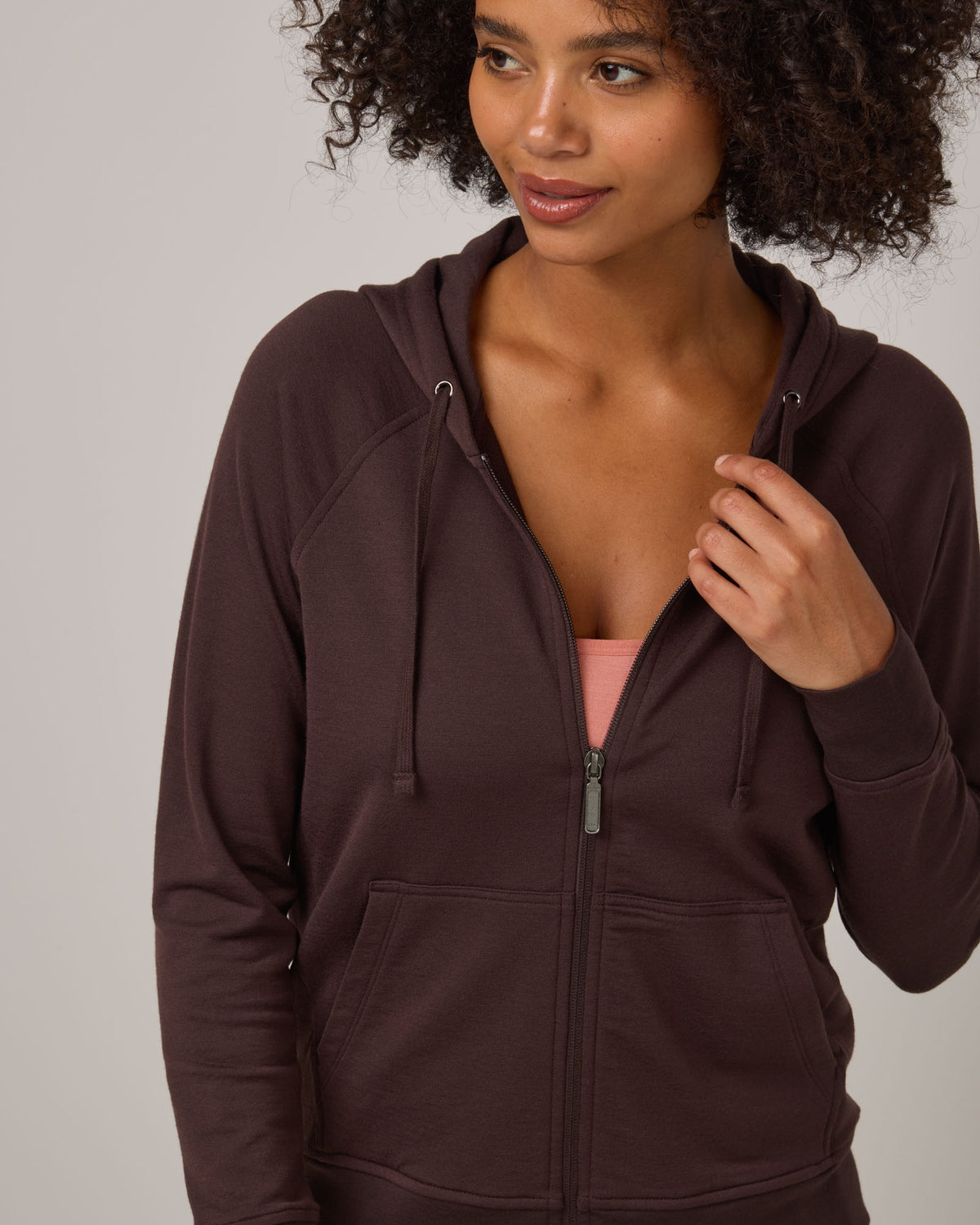 Model wearing Aspen Full-Zip Hoodie in Espresso, a dark brown color. Aspen Full-Zip Hoodie is a merino wool long sleeve zip hoodie with pockets available in sizes XS-3X.