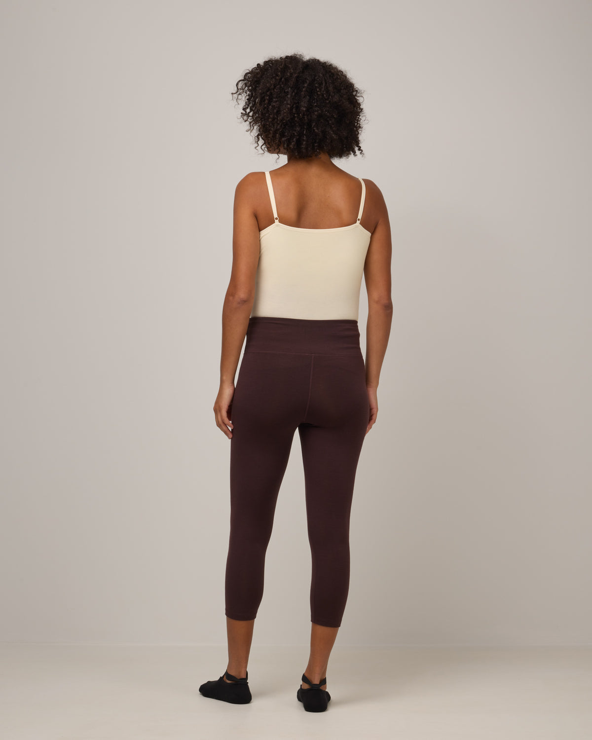 Model wearing Summit Crop Legging in Espresso, a dark brown color. Summit Crop Legging is a merino wool legging available in sizes XS-3X.