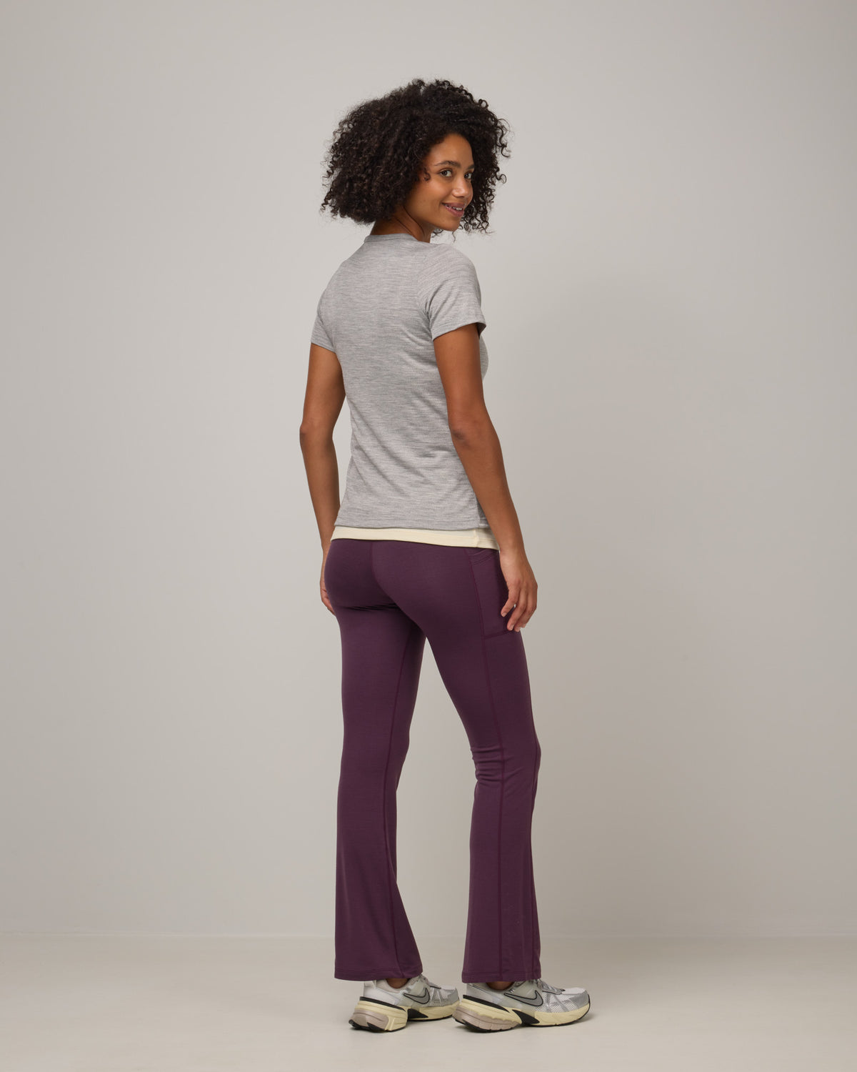 Model wearing Summit Straight Cut Pocket Legging in Dark Marionberry, a deep berry purple color. Summit Straight Cut Pocket Legging is a merino wool legging with pockets available in sizes XS-3X Regular, S-XXL Long.