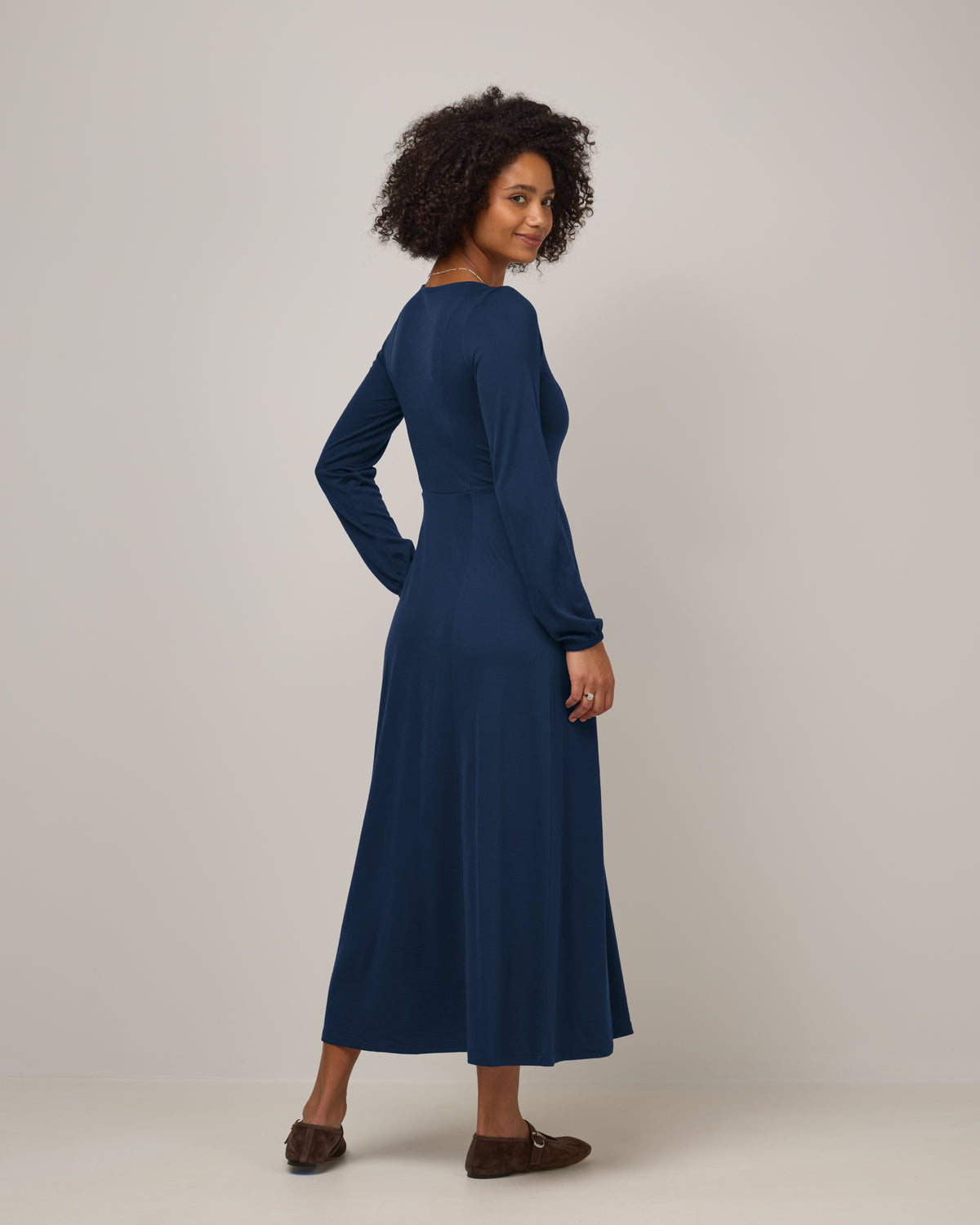 Model wearing Ahna Empire Waist Dress in Marine Blue, a deep royal blue color. Ahna Empire Waist Dress is a merino wool long sleeve, square neck, maxi fit & flare dress with pockets available in sizes XS-3X.