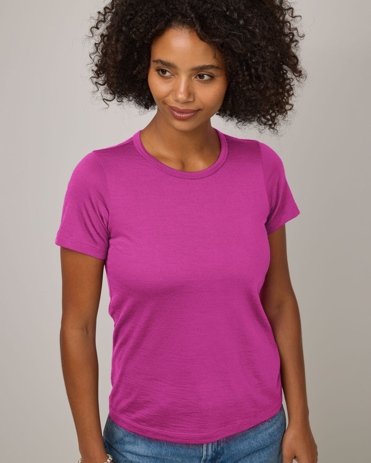Model wearing Cara Signature Fitted Tee in Petunia, a bright fuchsia pink color. Cara Signature Fitted Tee is a merino wool short sleeve, crew neck, slim fit tee available in sizes XS-3X.