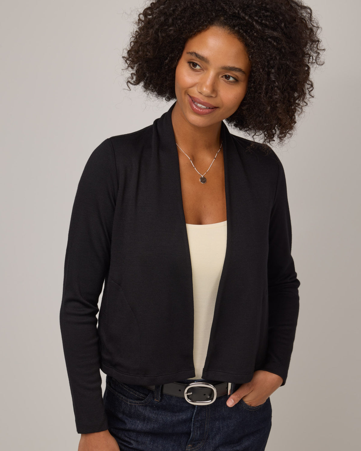 Model wearing Winona Crop Cardigan in Black. Winona Crop Cardigan is a merino wool cardigan with pockets available in sizes XS-XXL.