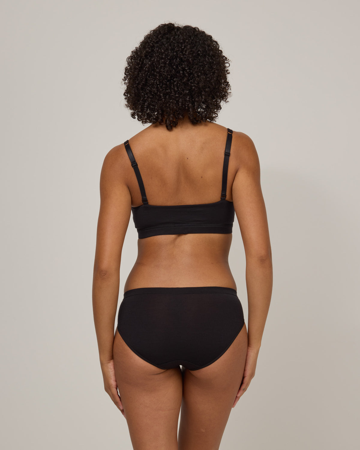 Model wearing Roam Convertible Wrap Bra in Black. Roam Convertible Wrap Bra is a merino wool underwear available in sizes XS-XXL.