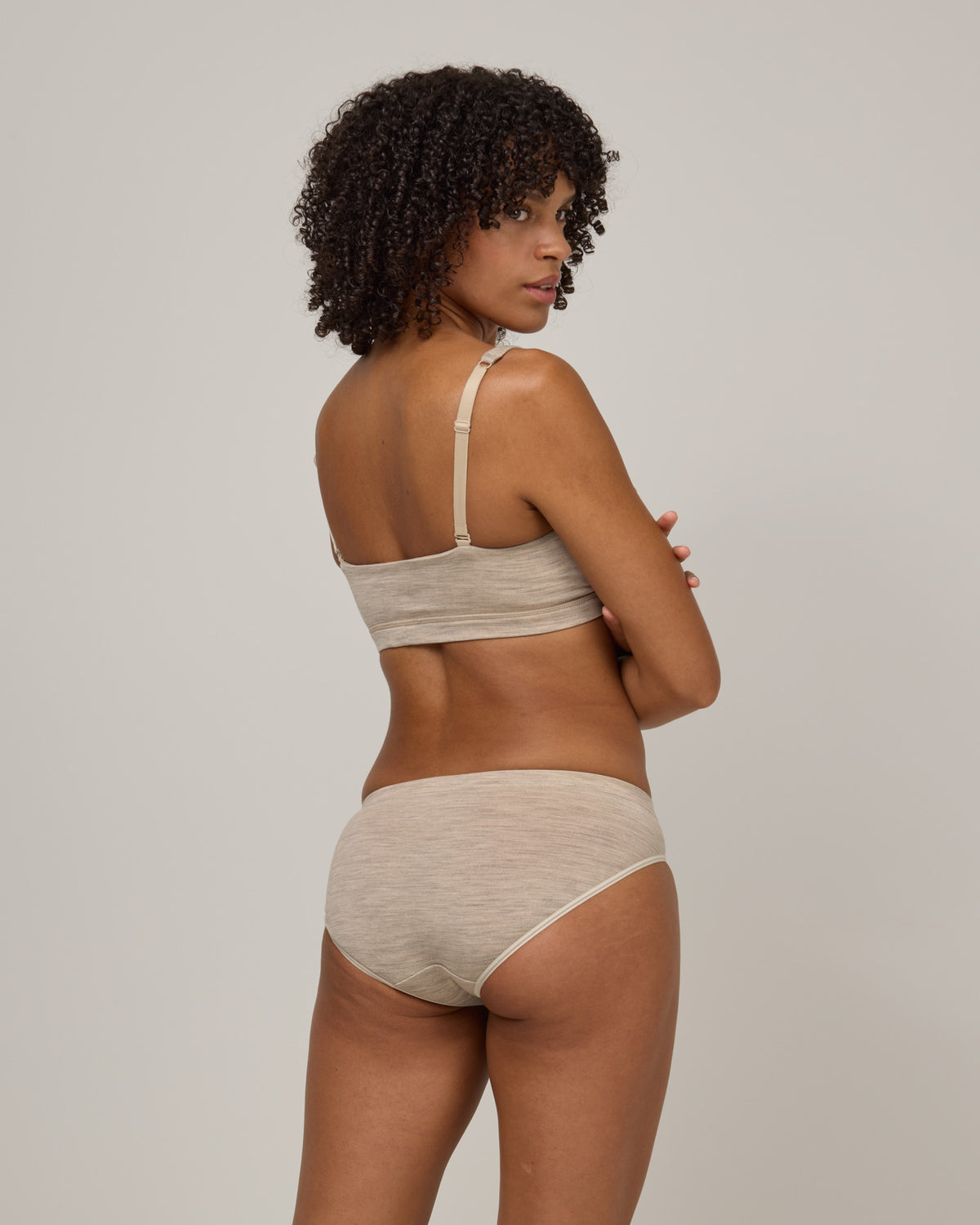 Model wearing Roam Bikini in Oatmeal Heather, a soft heathered cream color. Roam Bikini is a merino wool underwear available in sizes XS-3X.