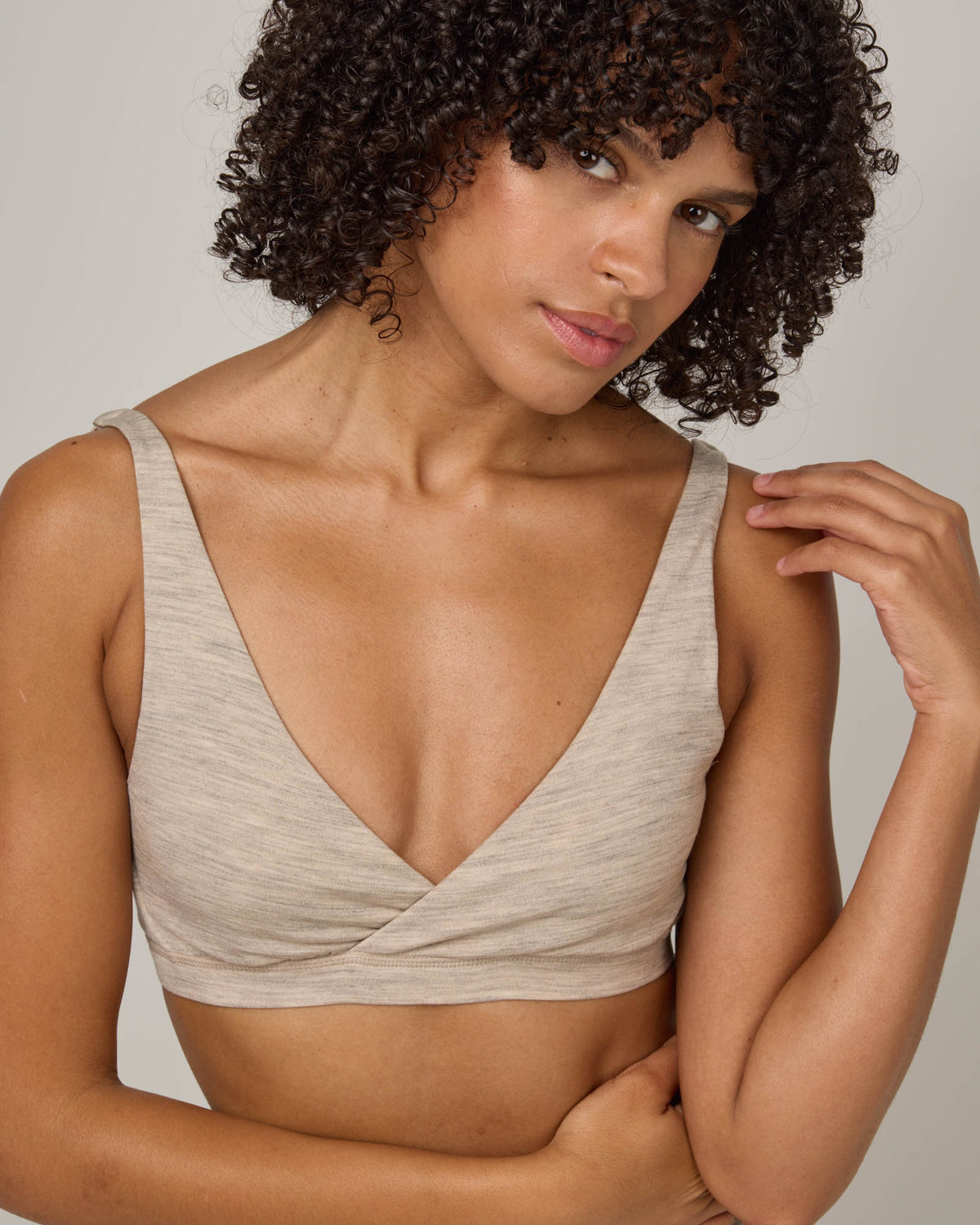 Model wearing Roam Convertible Wrap Bra in Oatmeal Heather, a soft heathered cream color. Roam Convertible Wrap Bra is a merino wool underwear available in sizes XS-XXL.