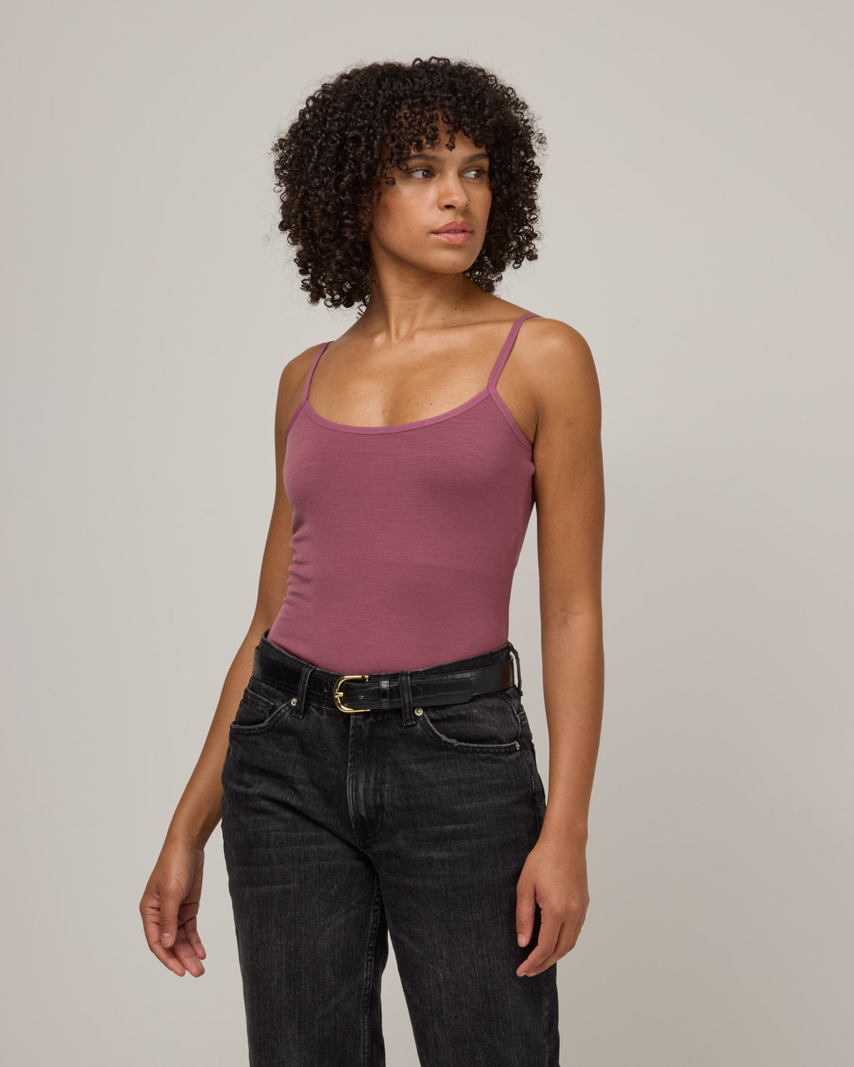 Model wearing Roam Shelf Bra Cami in Rosewood, a muted, dark pink-purple color . Roam Shelf Bra Cami is a merino wool sleeveless, scoop neck, slim fit top available in sizes XS-XXL.