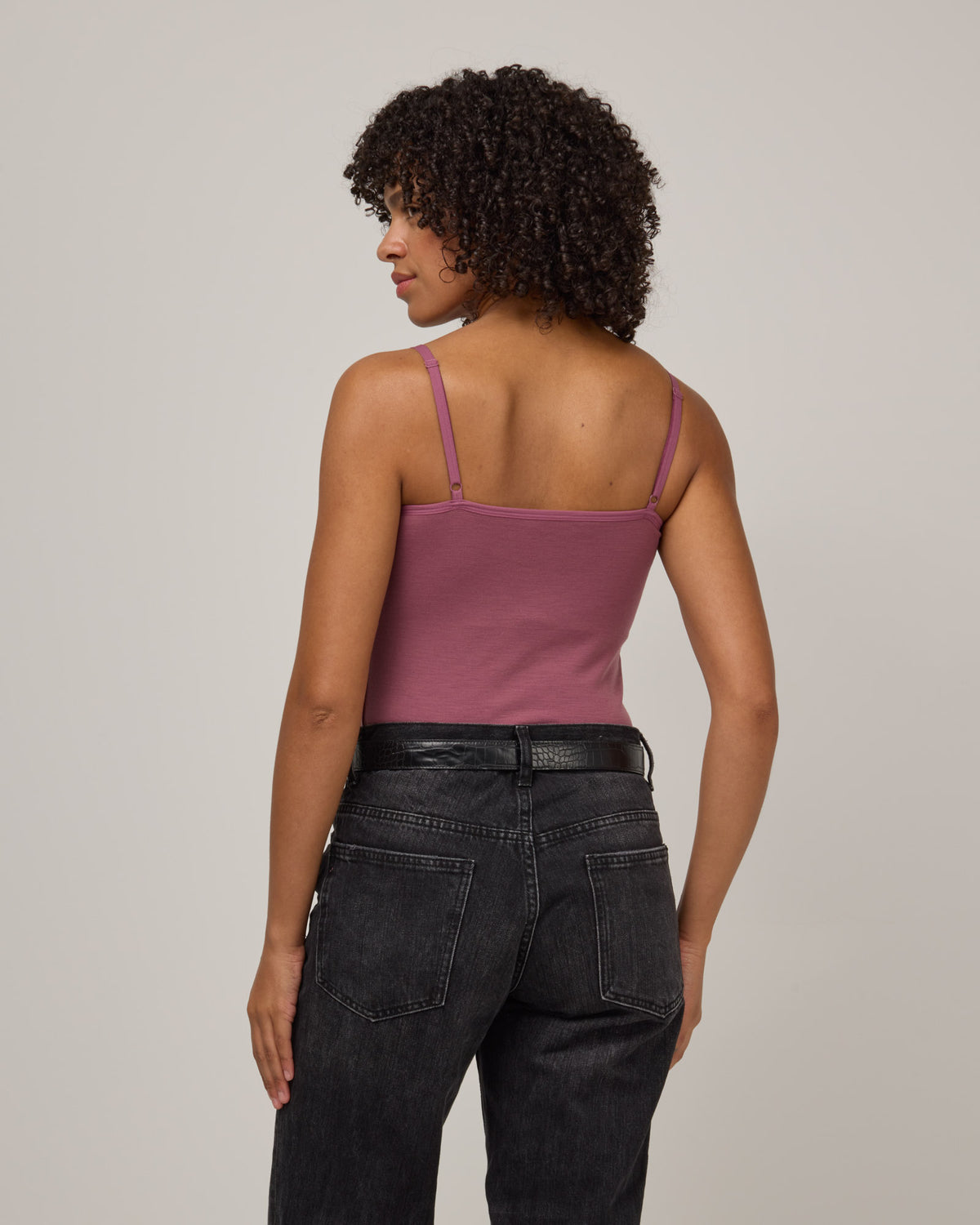 Model wearing Roam Shelf Bra Cami in Rosewood, a muted, dark pink-purple color . Roam Shelf Bra Cami is a merino wool sleeveless, scoop neck, slim fit top available in sizes XS-XXL.