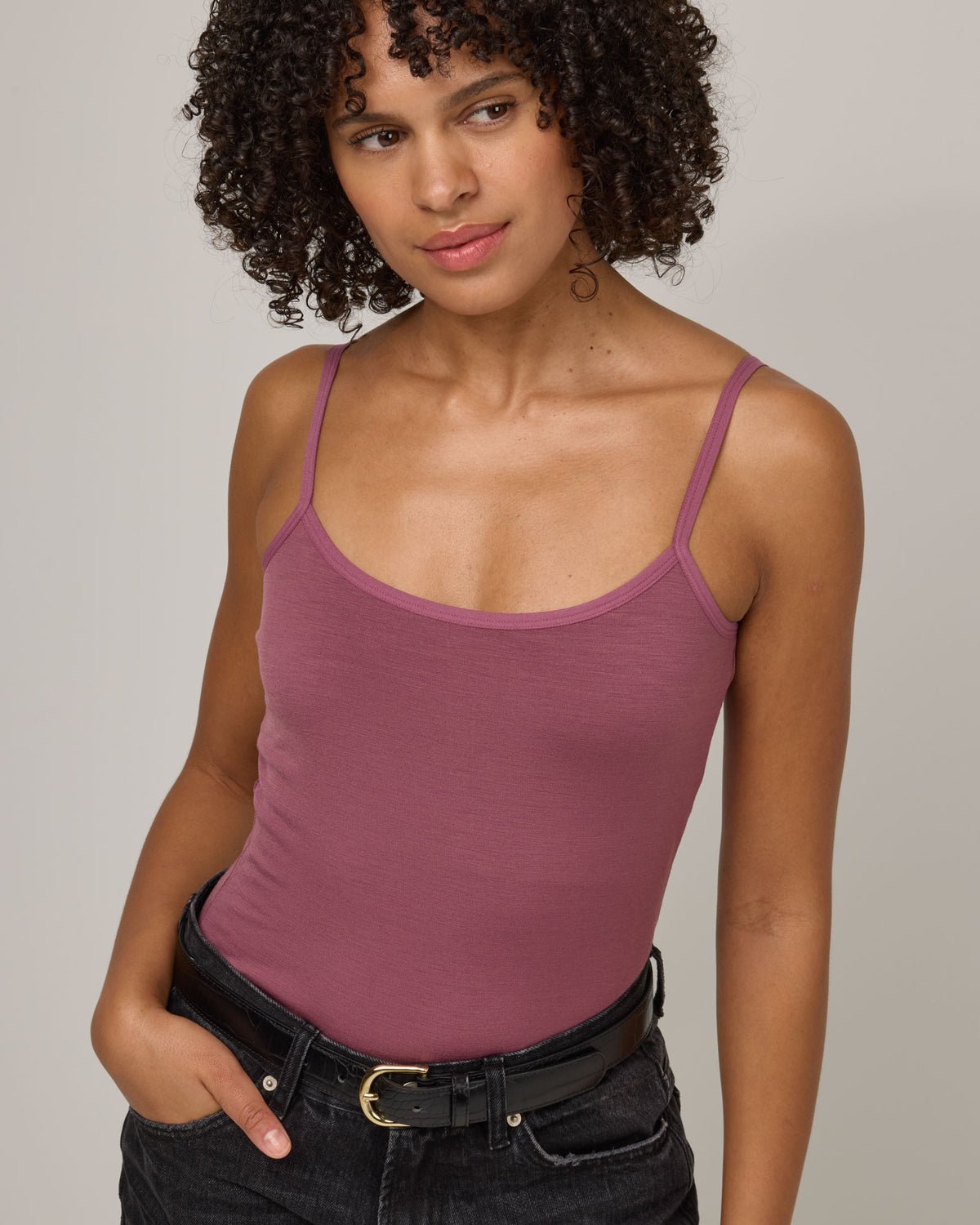 Model wearing Roam Shelf Bra Cami in Rosewood, a muted, dark pink-purple color . Roam Shelf Bra Cami is a merino wool sleeveless, scoop neck, slim fit top available in sizes XS-XXL.