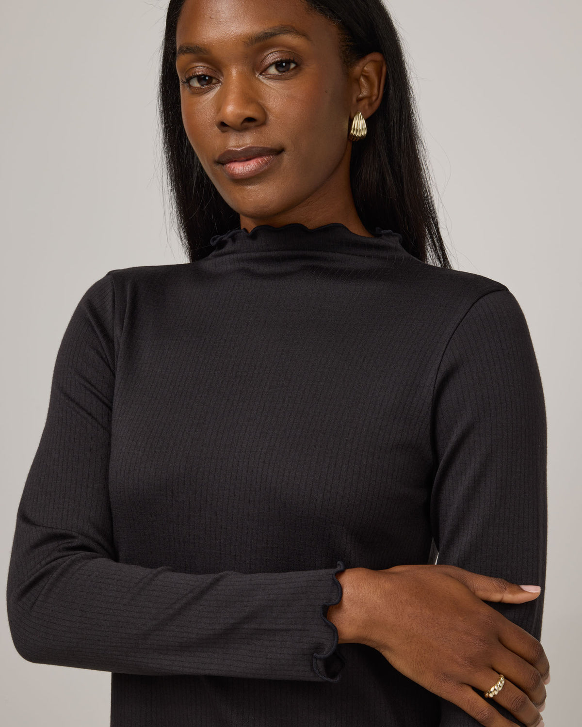 Model wearing Daphne Ribbed Dress in Black. Daphne Ribbed Dress is a merino wool long sleeve, turtleneck, knee length fitted dress available in sizes XS-XXL.