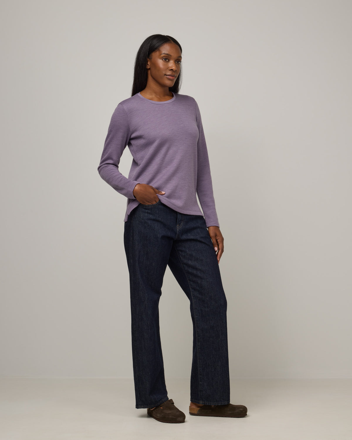 Model wearing Rayne Double Knit Ribbed Top in Purple Sage, a soft, muted purple color. Rayne Double Knit Ribbed Top is a merino wool long sleeve, crew neck, slim fit top available in sizes XS-3X.
