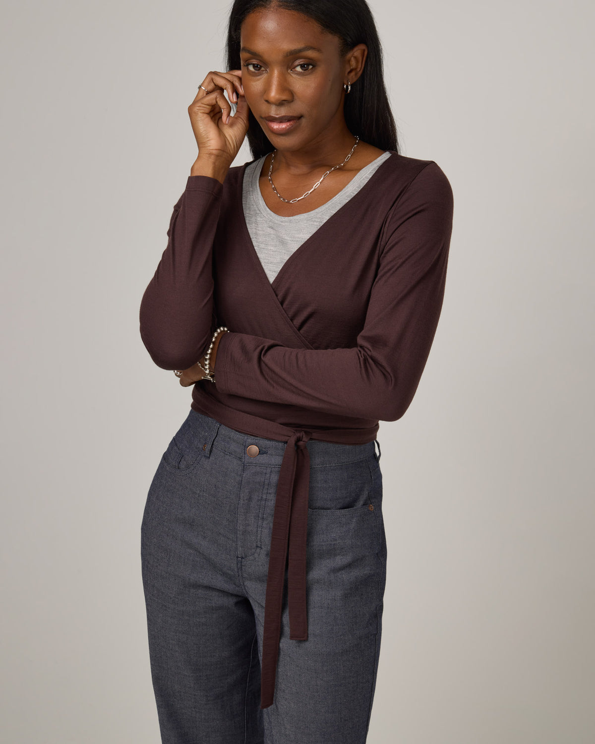 Model wearing Natalia Wrap Top in Espresso, a dark brown color. Natalia Wrap Top is a merino wool long sleeve, v-neck, slim fit top available in sizes XS-3X.