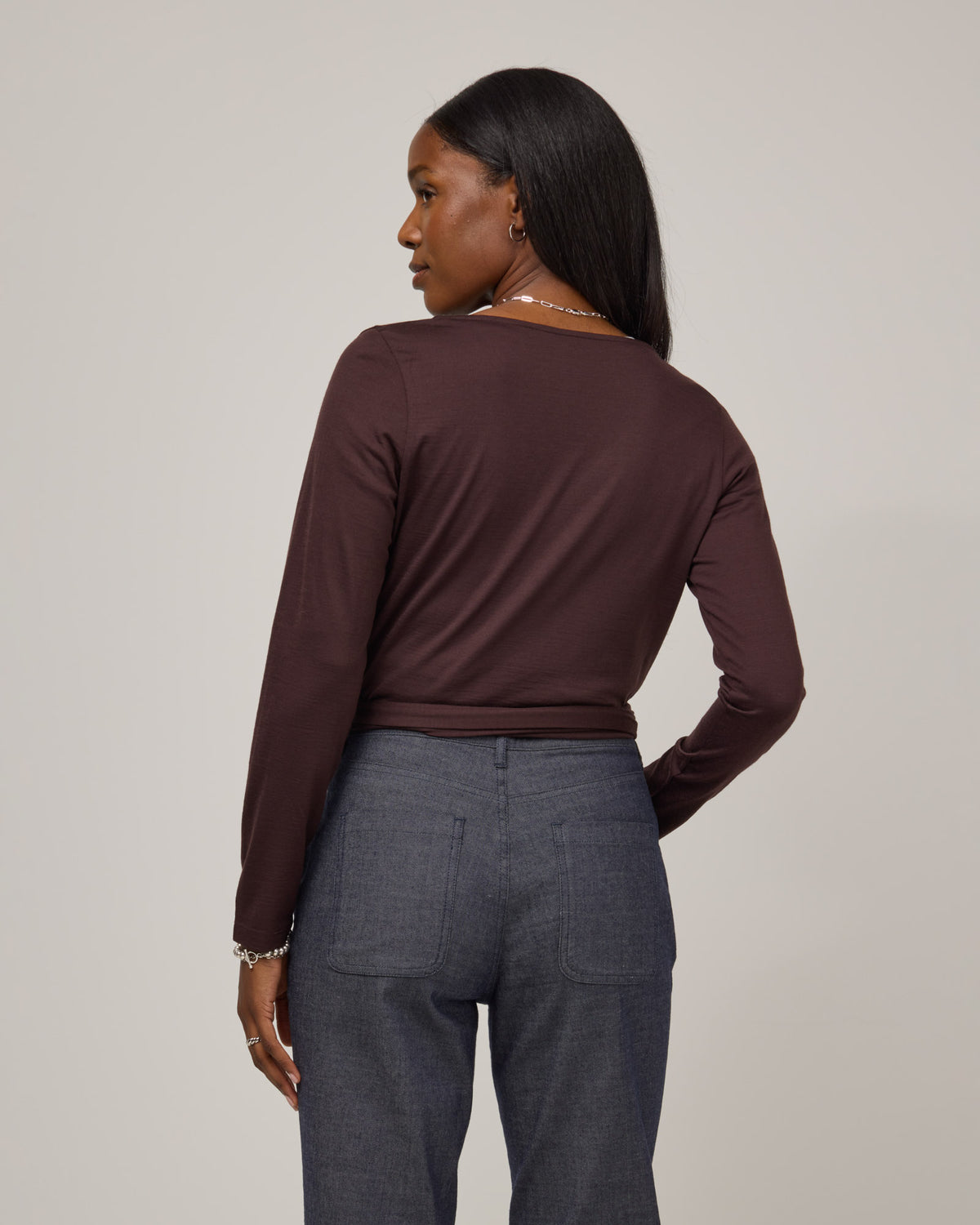 Model wearing Natalia Wrap Top in Espresso, a dark brown color. Natalia Wrap Top is a merino wool long sleeve, v-neck, slim fit top available in sizes XS-3X.