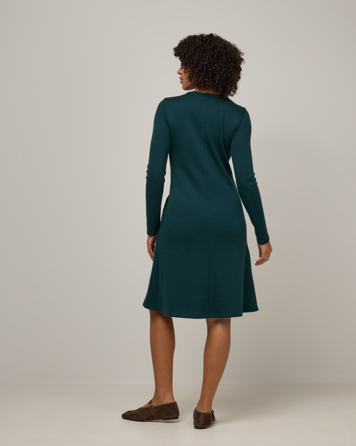 Model wearing Bethany Double Knit Ribbed Dress in Pine, a saturated forest green color. Bethany Double Knit Ribbed Dress is a merino wool long sleeve, crew neck, midi swing dress with pockets available in sizes XS-3X.