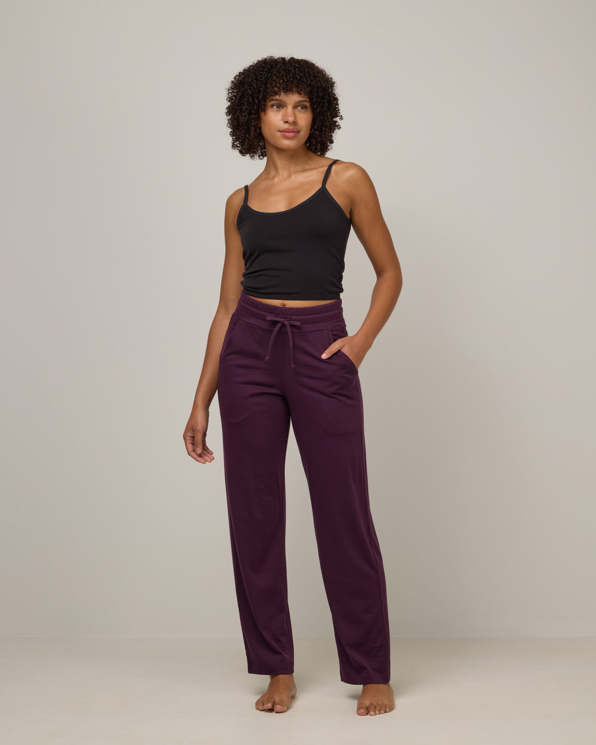 Model wearing Twilight Sleep Pant in Marionberry, a dark berry purple color. Twilight Sleep Pant is a merino wool pant with pockets available in sizes XS-XXL.
