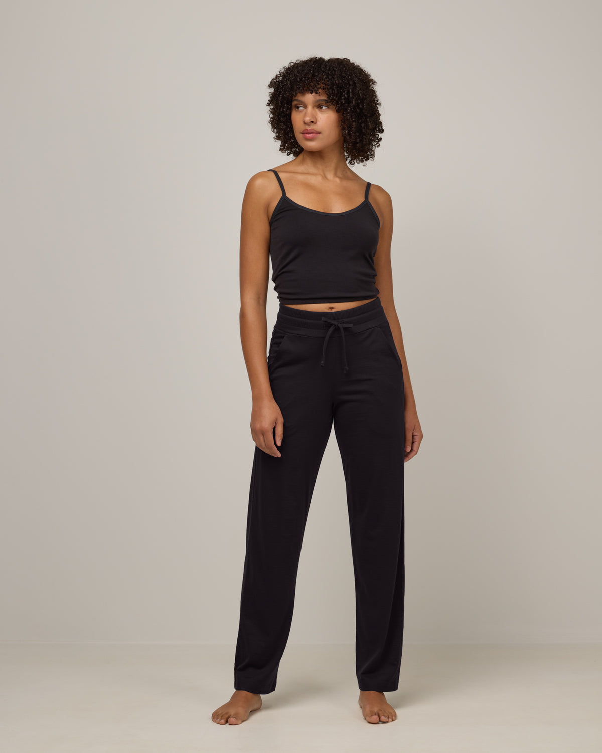 Model wearing Twilight Sleep Pant in Black. Twilight Sleep Pant is a merino wool pant with pockets available in sizes XS-XXL.