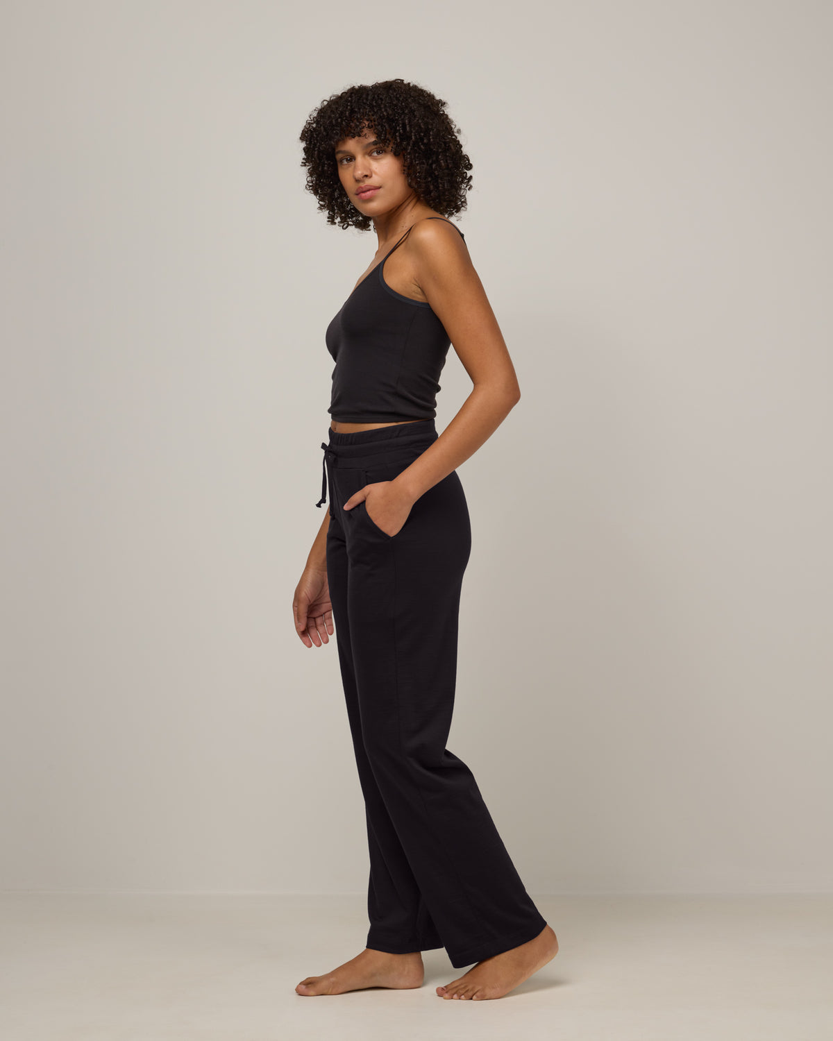 Model wearing Twilight Sleep Pant in Black. Twilight Sleep Pant is a merino wool pant with pockets available in sizes XS-XXL.
