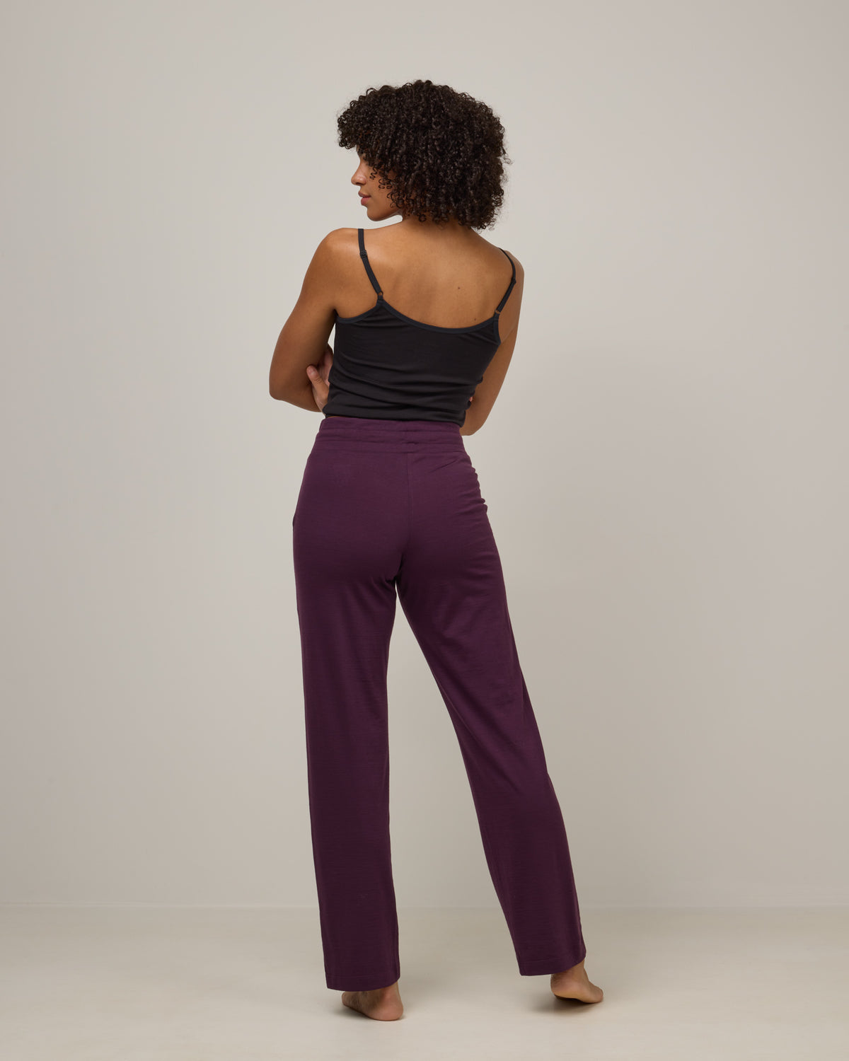 Model wearing Twilight Sleep Pant in Marionberry, a dark berry purple color. Twilight Sleep Pant is a merino wool pant with pockets available in sizes XS-XXL.
