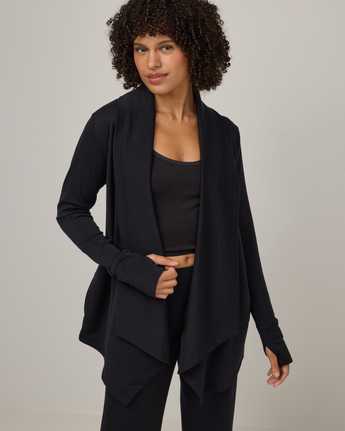 Model wearing Aspen Cardigan in Black. Aspen Cardigan is a merino wool long sleevecardigan with pockets available in sizes XS-3X.