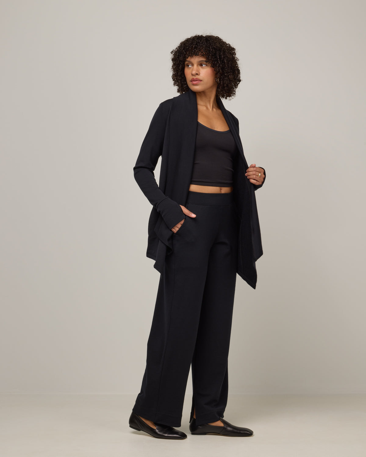 Model wearing Aspen Cardigan in Black. Aspen Cardigan is a merino wool long sleevecardigan with pockets available in sizes XS-3X.