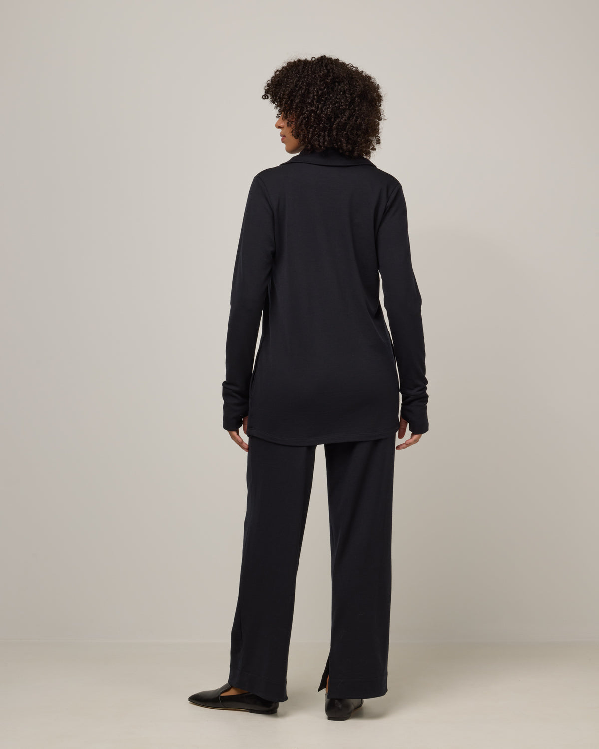 Model wearing Aspen Cardigan in Black. Aspen Cardigan is a merino wool long sleevecardigan with pockets available in sizes XS-3X.