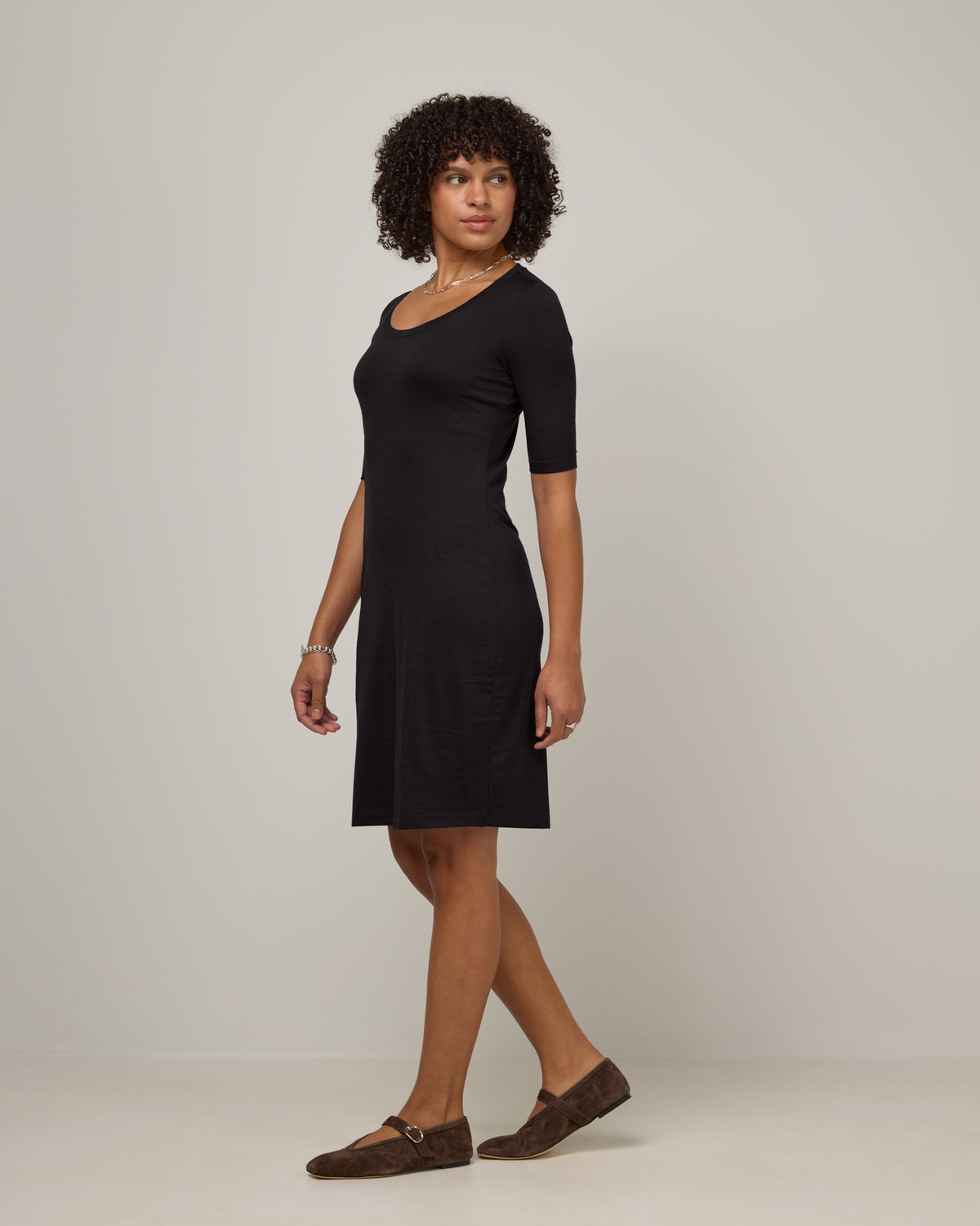Model wearing Chloe Fitted Dress in Black. Chloe Fitted Dress is a merino wool short sleeve, scoop neck, knee length fitted dress available in sizes XS-XXL.
