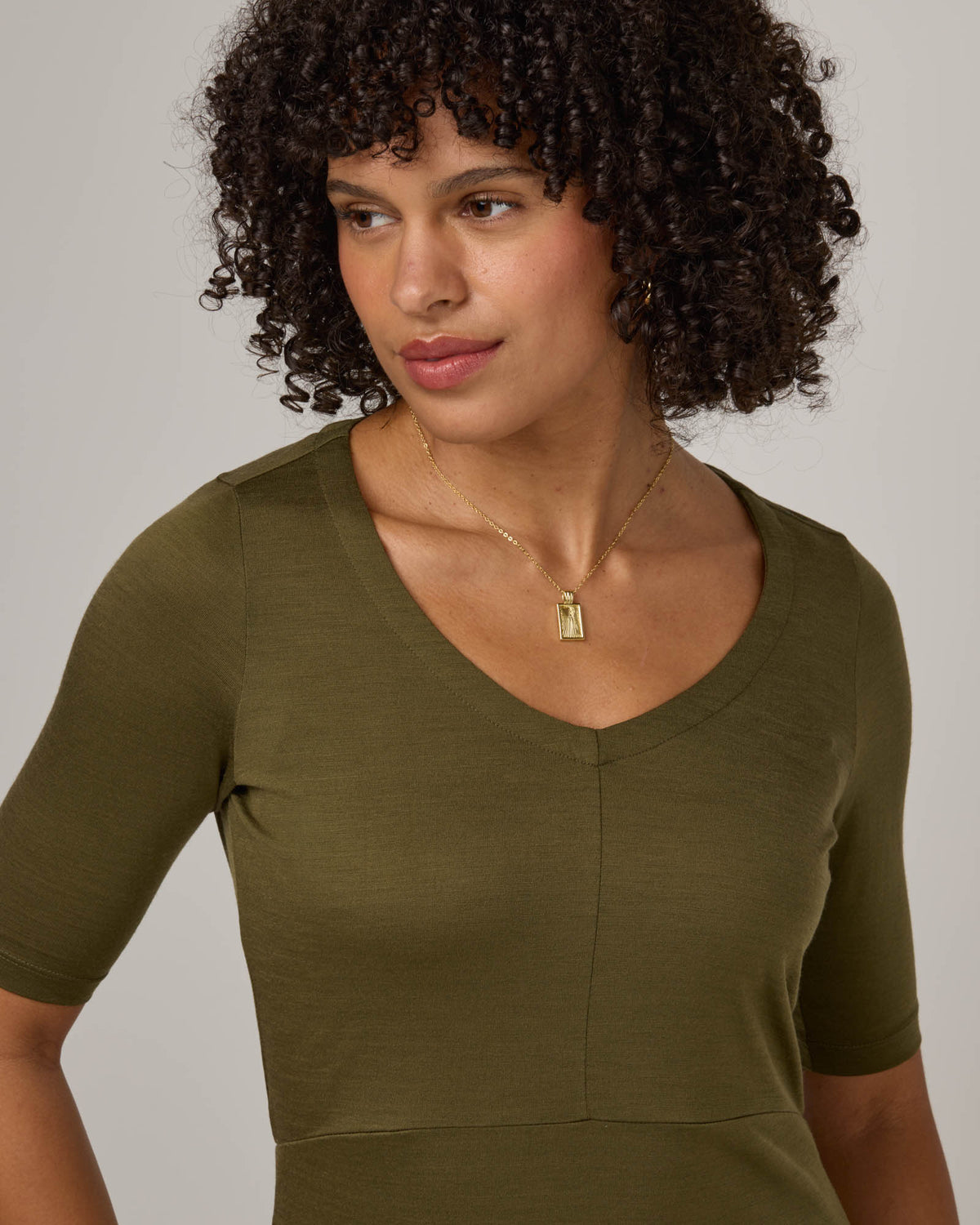 Model wearing London Fitted Dress in Olive. London Fitted Dress is a merino wool short sleeve, v-neck, midi fitted dress available in sizes XS-3X Regular, XS-XL Petite.
