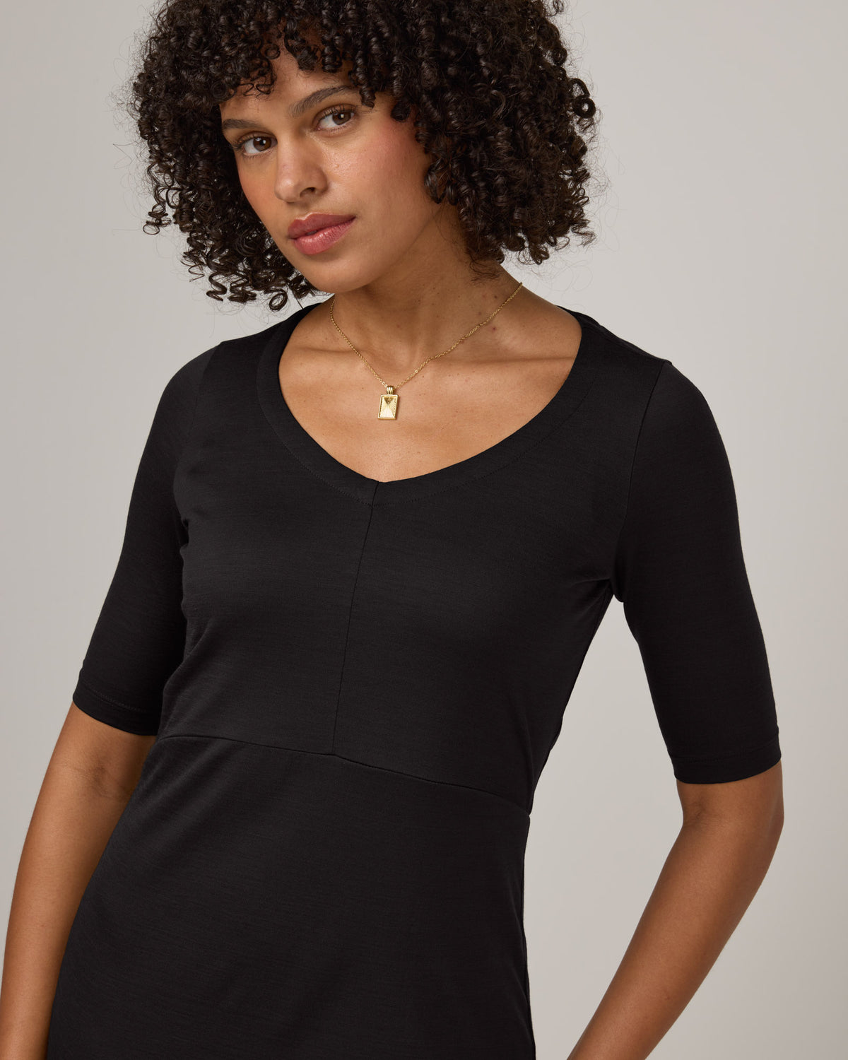 Model wearing London Fitted Dress in Black. London Fitted Dress is a merino wool short sleeve, v-neck, midi fitted dress available in sizes XS-3X Regular, XS-XL Petite.