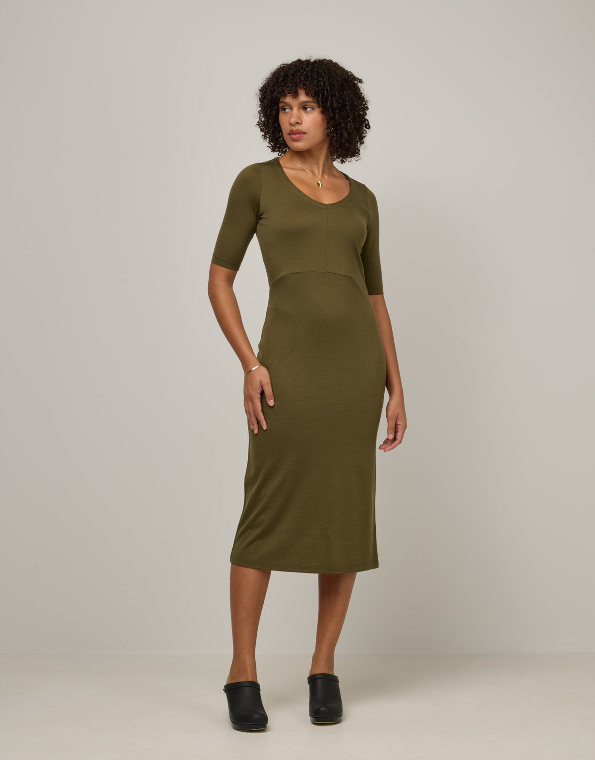 Model wearing London Fitted Dress in Olive. London Fitted Dress is a merino wool short sleeve, v-neck, midi fitted dress available in sizes XS-3X Regular, XS-XL Petite.