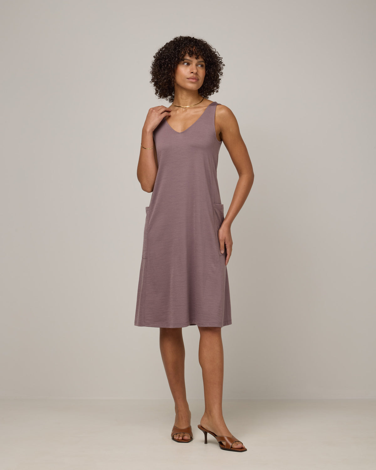 Model wearing Summer Reversible Dress in Lavender, a dusky, muted purple color. Summer Reversible Dress is a merino wool sleeveless, reversible, midi swing dress with pockets available in sizes XS-3X.