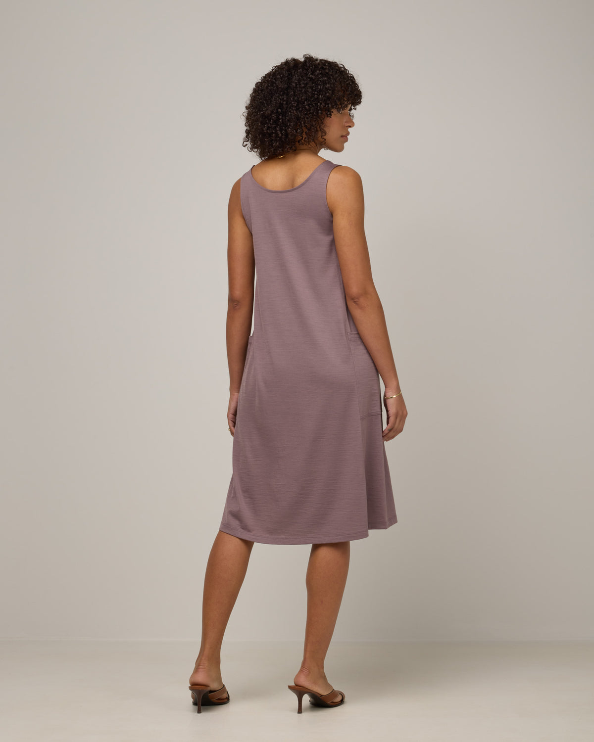 Model wearing Summer Reversible Dress in Lavender, a dusky, muted purple color. Summer Reversible Dress is a merino wool sleeveless, reversible, midi swing dress with pockets available in sizes XS-3X.