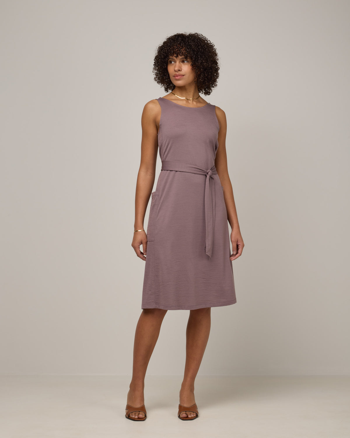 Model wearing Summer Reversible Dress in Lavender, a dusky, muted purple color. Summer Reversible Dress is a merino wool sleeveless, reversible, midi swing dress with pockets available in sizes XS-3X.