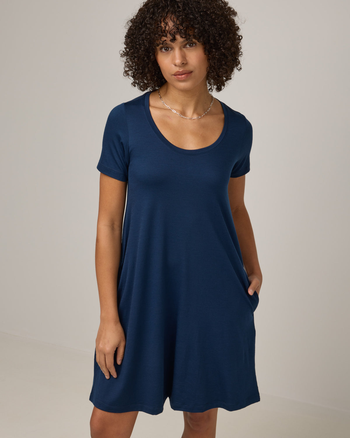 Model wearing Maggie Swing Dress in Marine Blue, a deep royal blue color. Maggie Swing Dress is a merino wool short sleeve, scoop neck, knee length swing dress with pockets available in sizes XS-3X Regular, XS-3X Long.