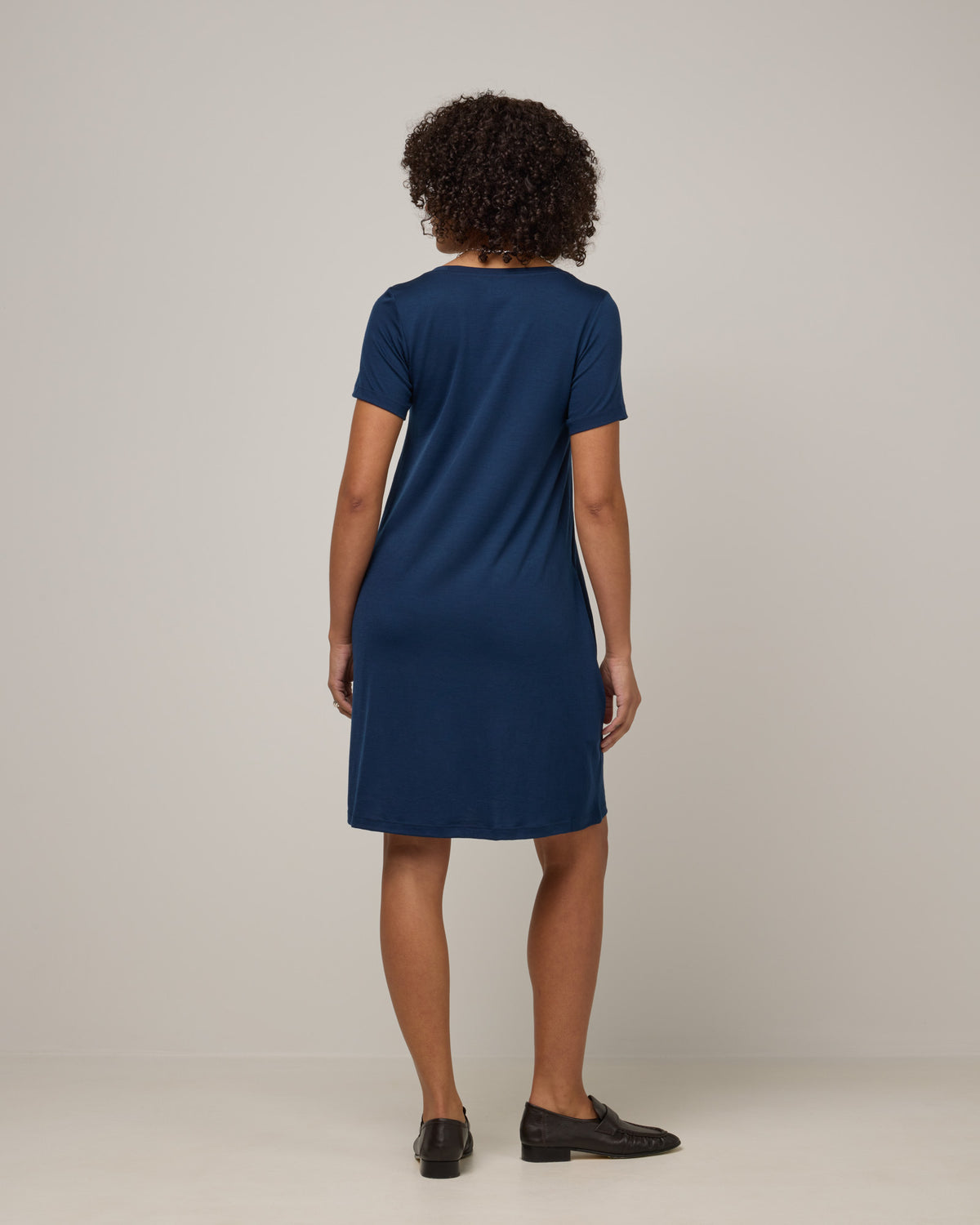 Model wearing Maggie Swing Dress in Marine Blue, a deep royal blue color. Maggie Swing Dress is a merino wool short sleeve, scoop neck, knee length swing dress with pockets available in sizes XS-3X Regular, XS-3X Long.